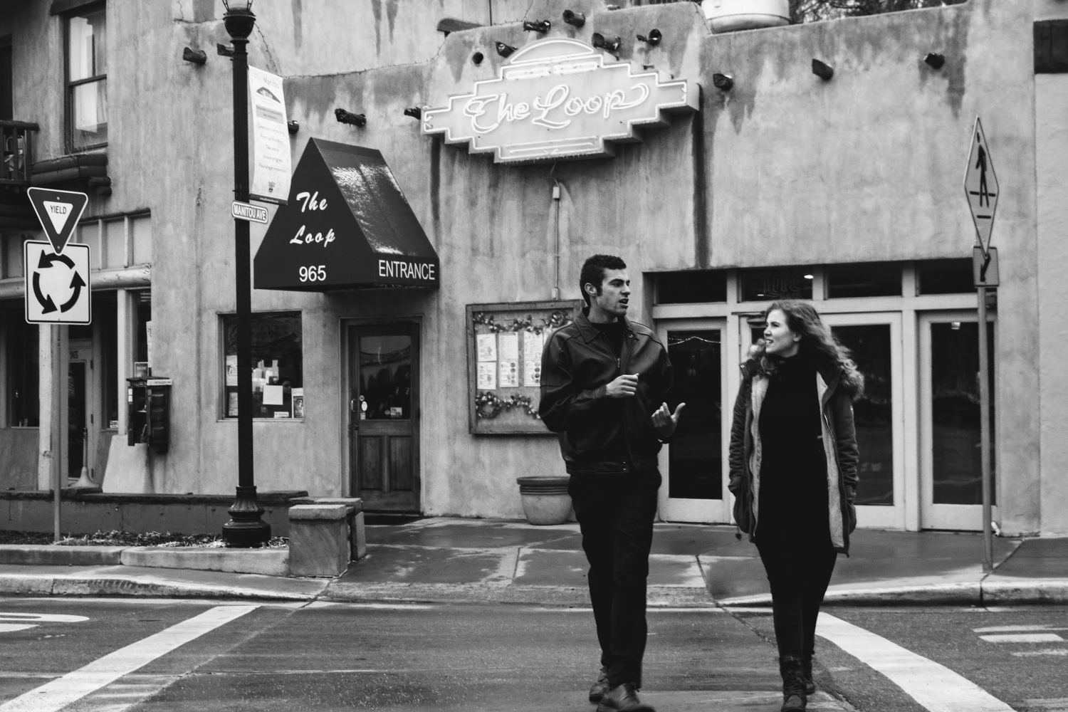 Two silhouettes walk together down a monochrome urban street.