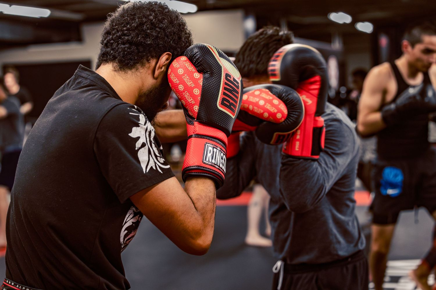 Kickboxers working on fight techniques during an intense training session in a modern martial arts gym.