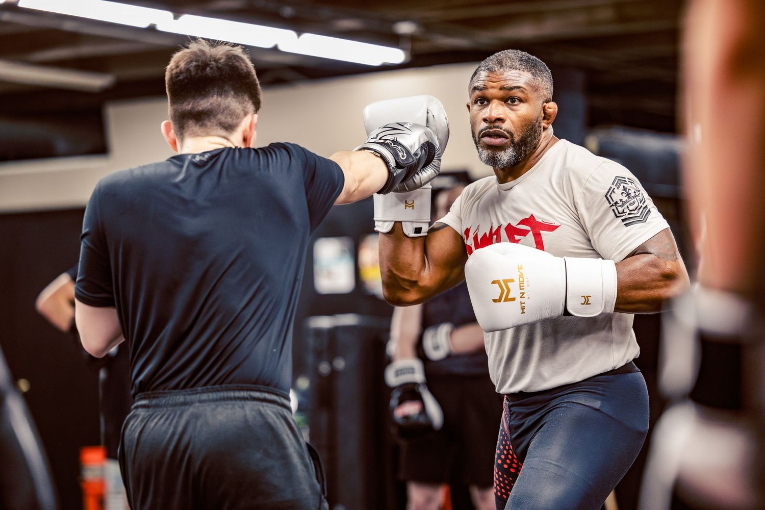 Training partners working on boxing fundamentals and footwork in a martial arts gym.