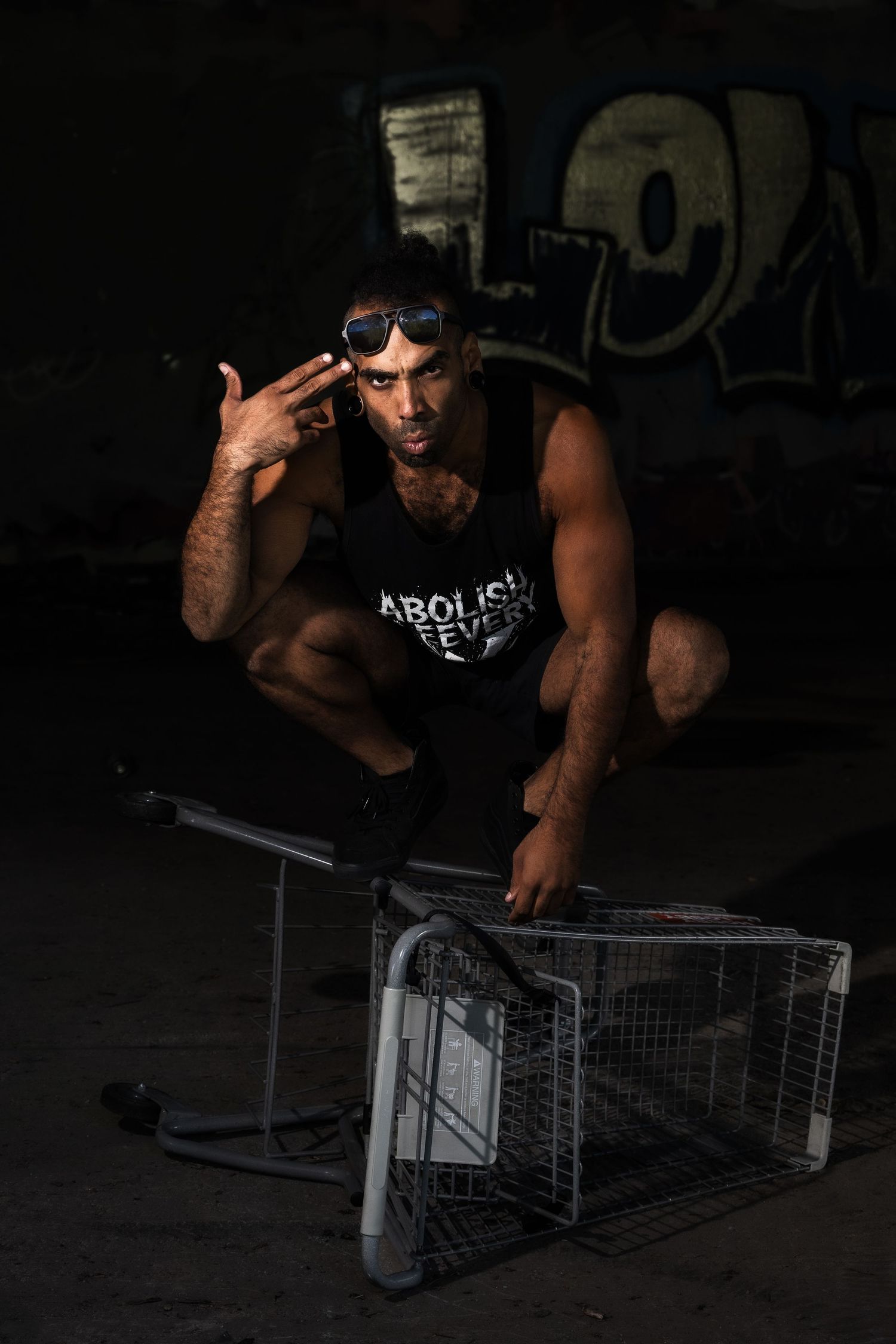 Athletic figure performing parkour moves over metal shopping carts in dark urban setting.