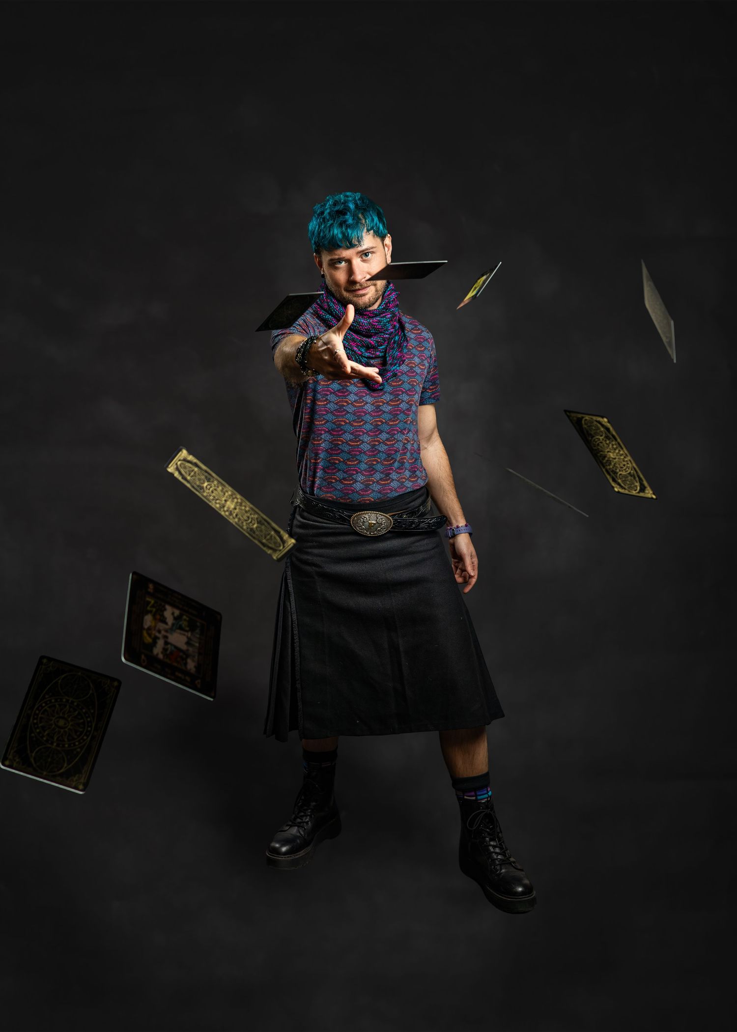 Person with teal hair in a kilt throwing playing cards against a dark background.