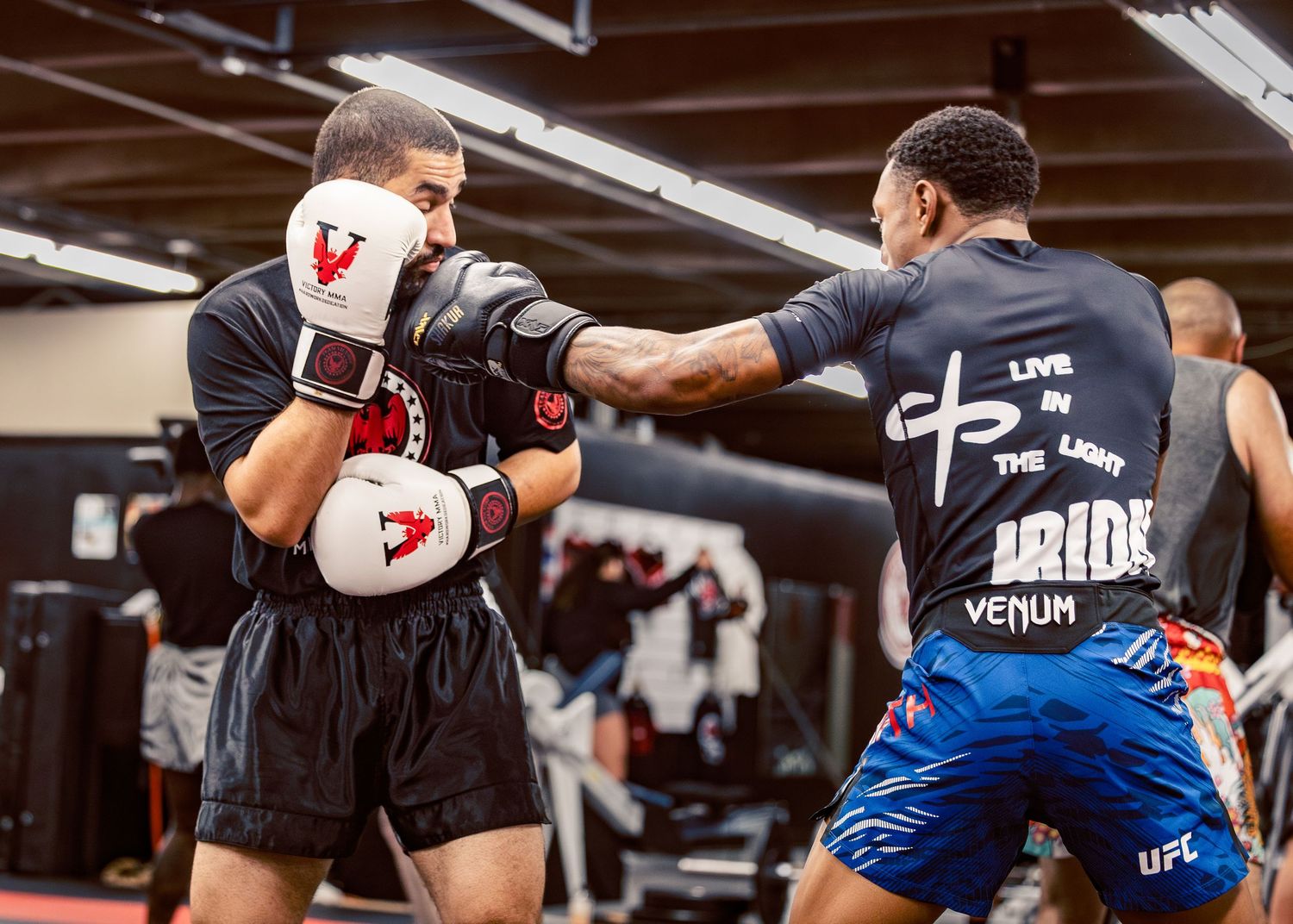 Boxers practicing combinations and sparring techniques in a modern training gym with boxing equipment.