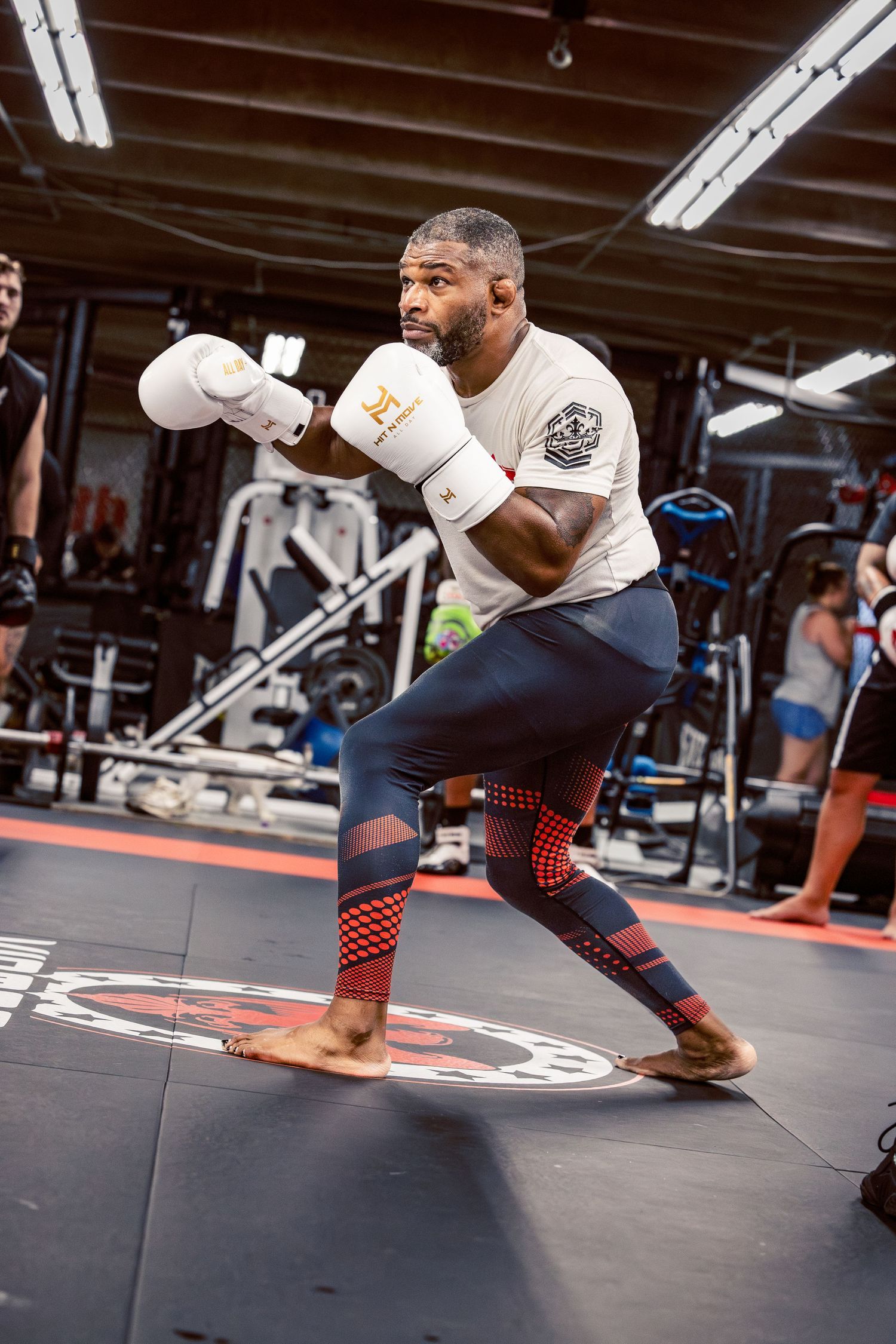 Fighter demonstrating dynamic footwork drills on a gym mat with red markings.