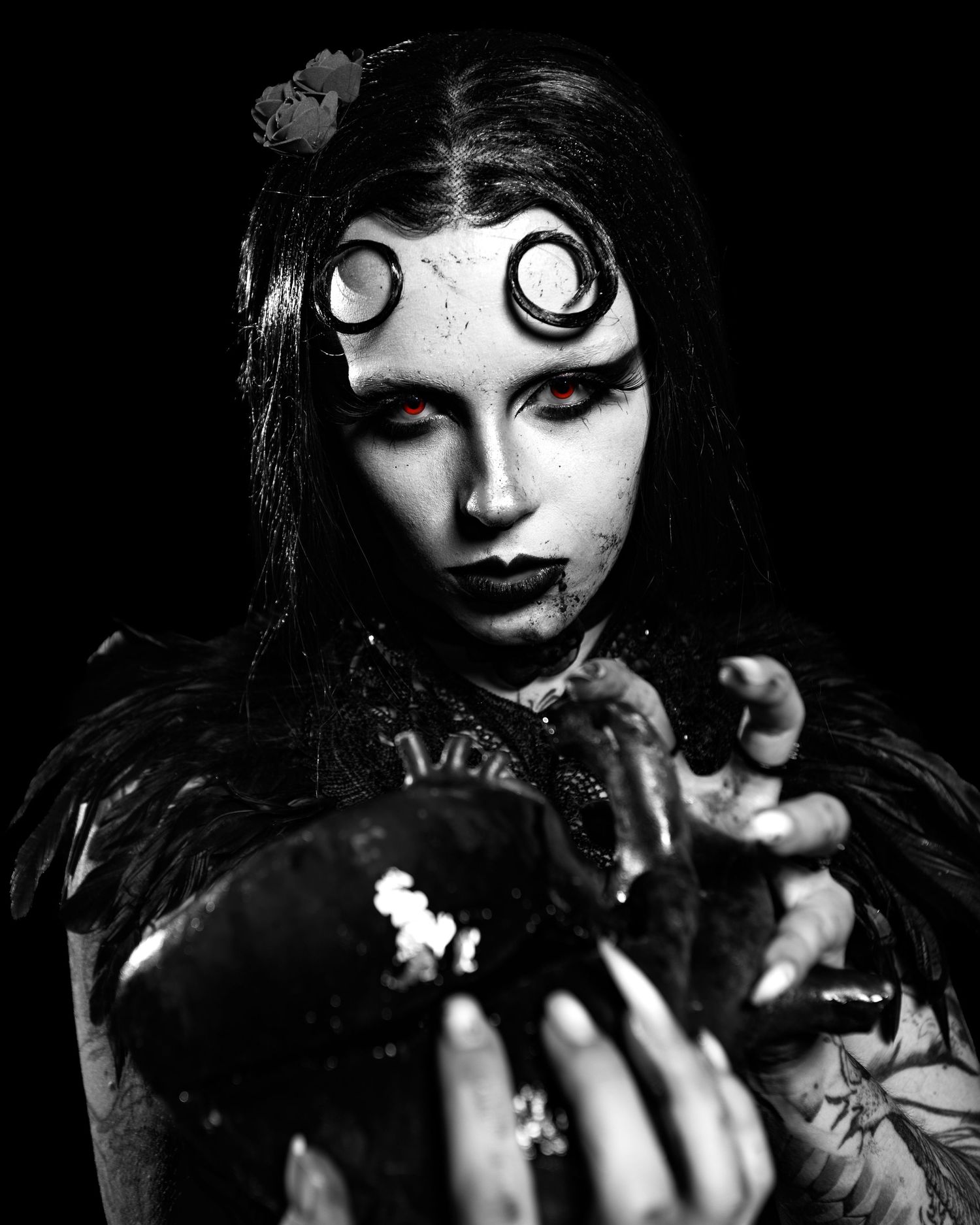 Black and white gothic portrait of woman with spiral eye makeup holding dark object, dramatic horror-themed artistic photography.