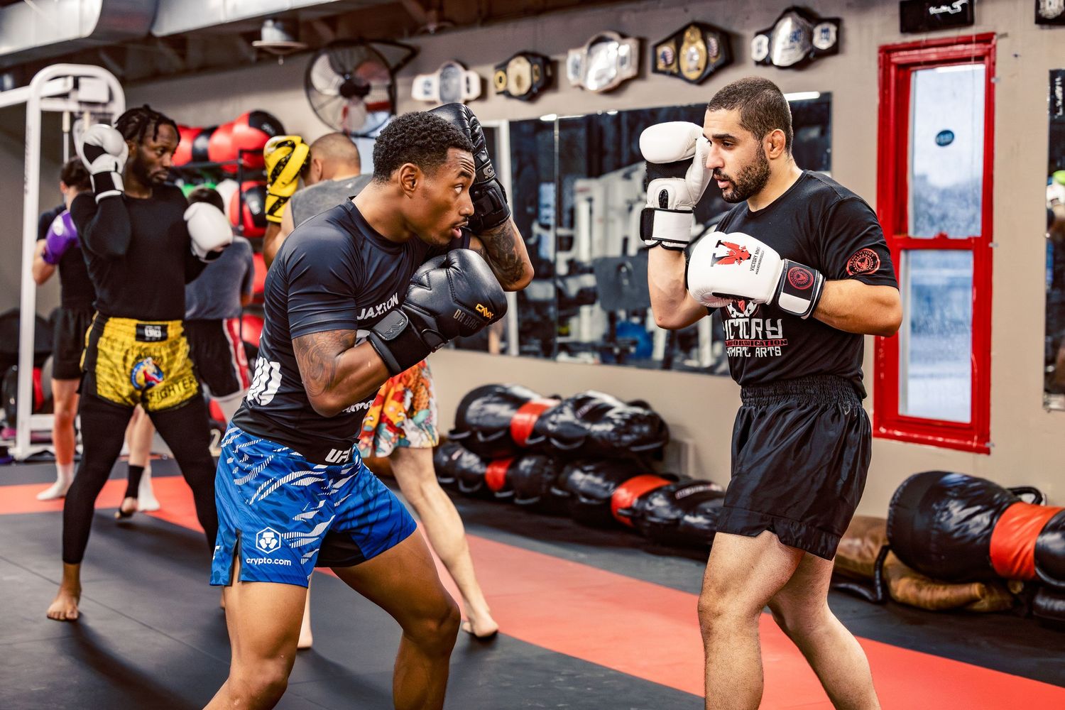 Students practicing kickboxing moves during a group training session in a professional fight gym.