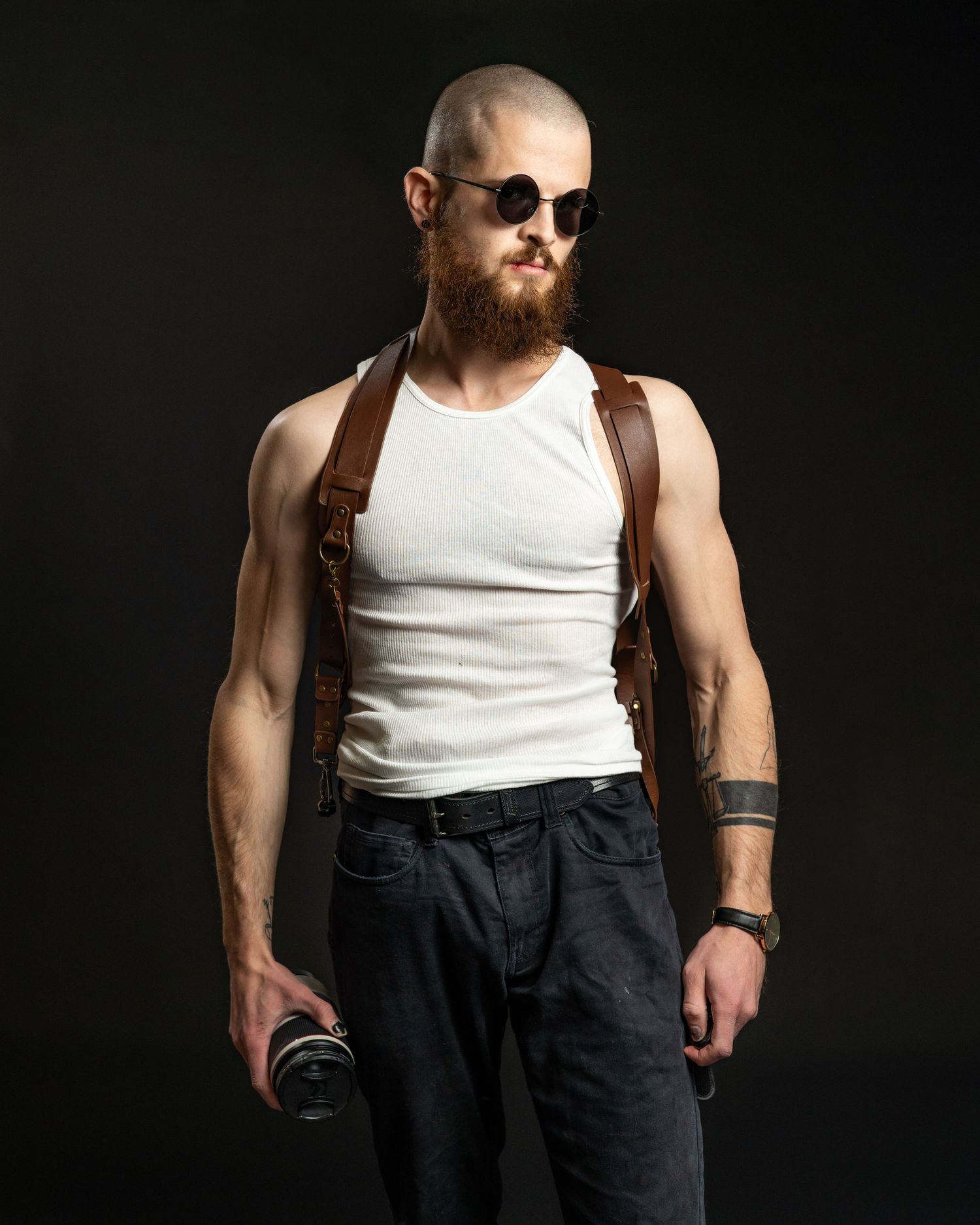 Side view of someone wearing sunglasses and a white tank top posing dramatically on dark background.