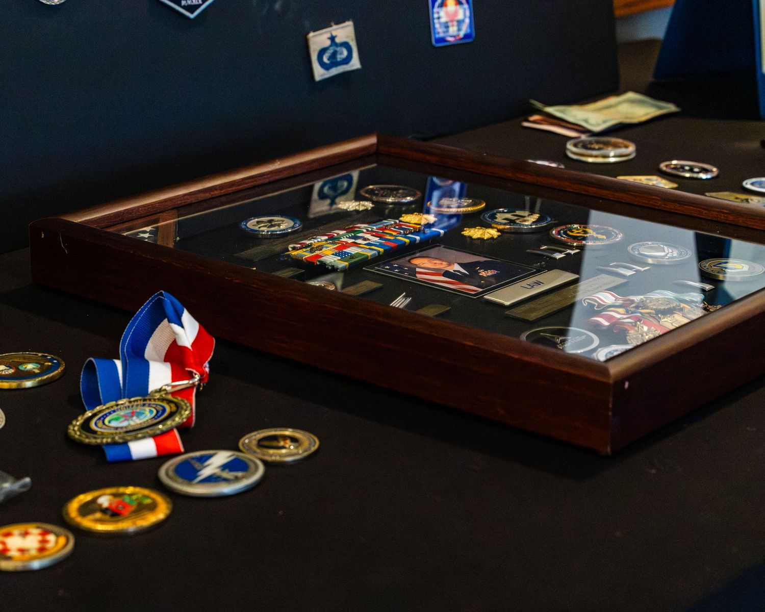 Military medals, patches and awards displayed on dark wooden surface.