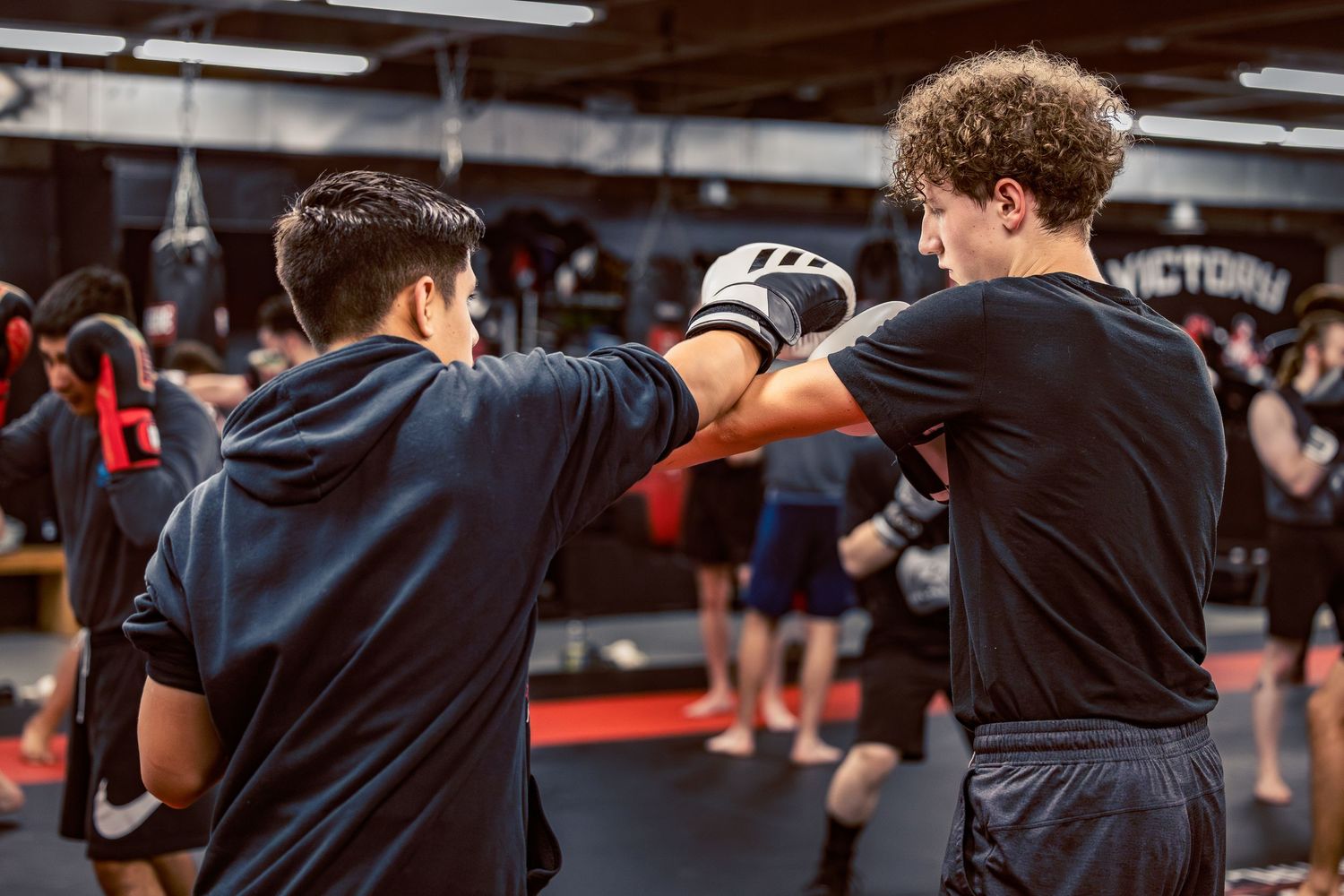 Training partners practicing boxing techniques in a modern gym setting.