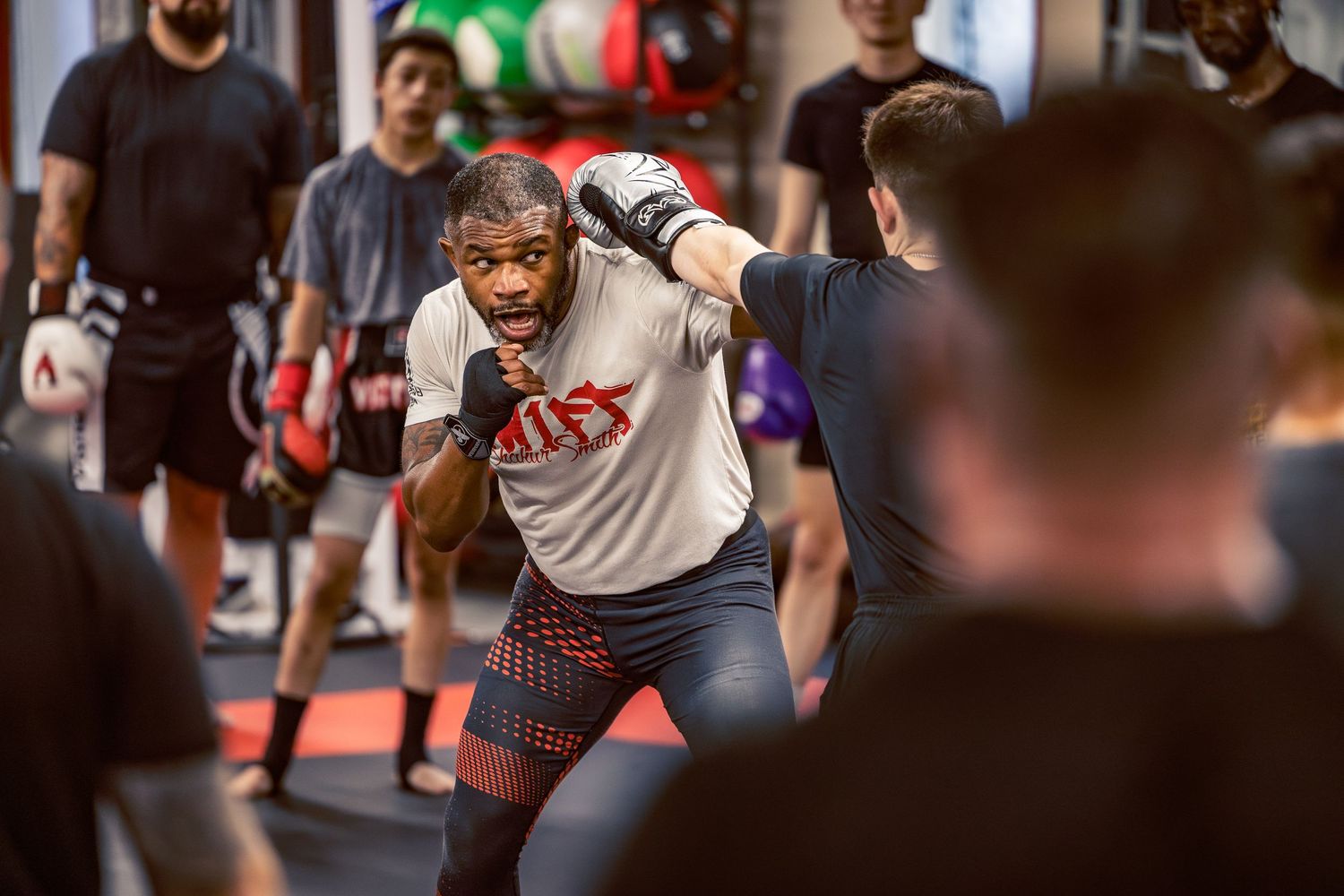 Mixed martial arts practitioners sparring and practicing combinations in a professional gym environment.