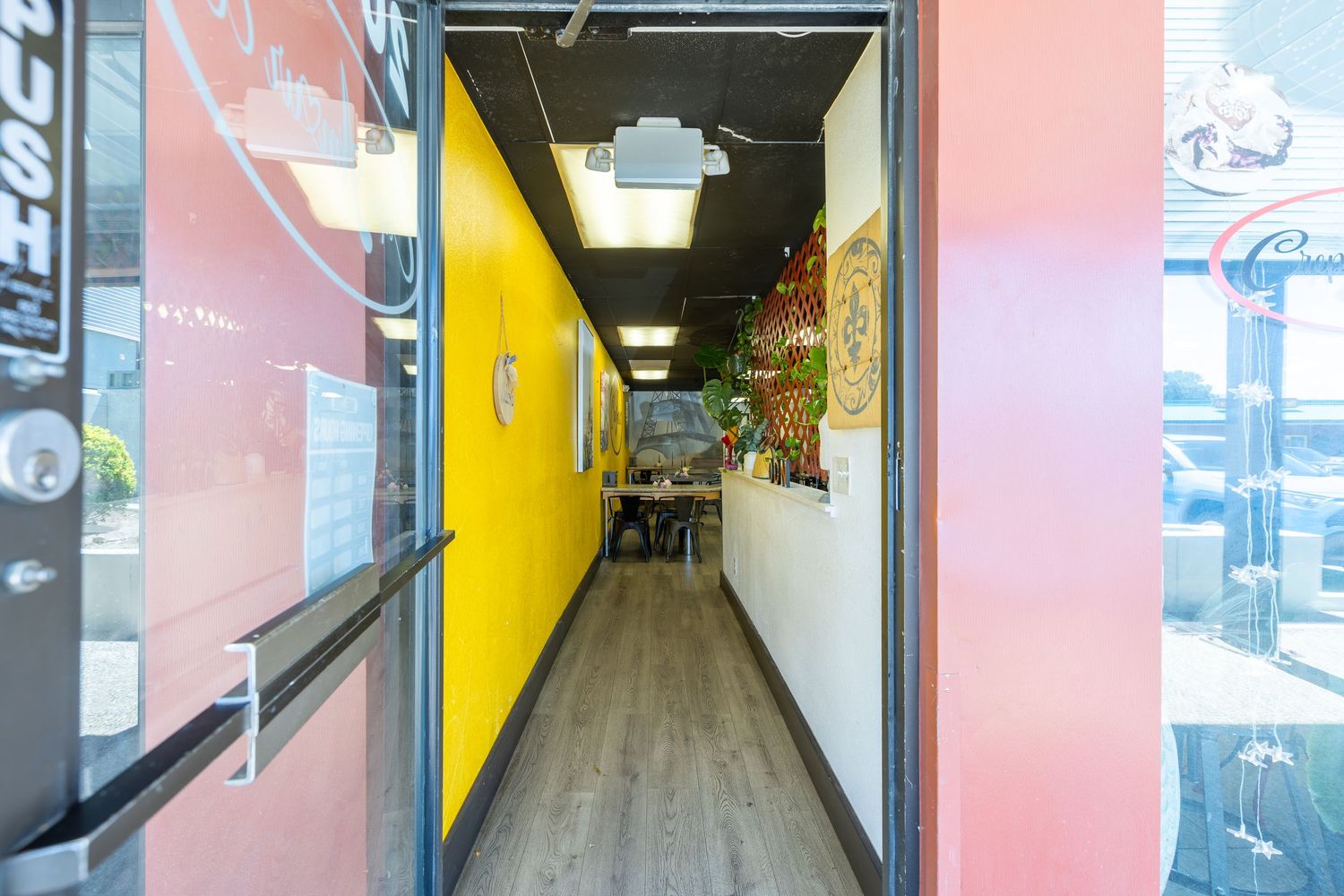 Bright hallway entrance with yellow walls and wood floors leading into a colorful restaurant interior.