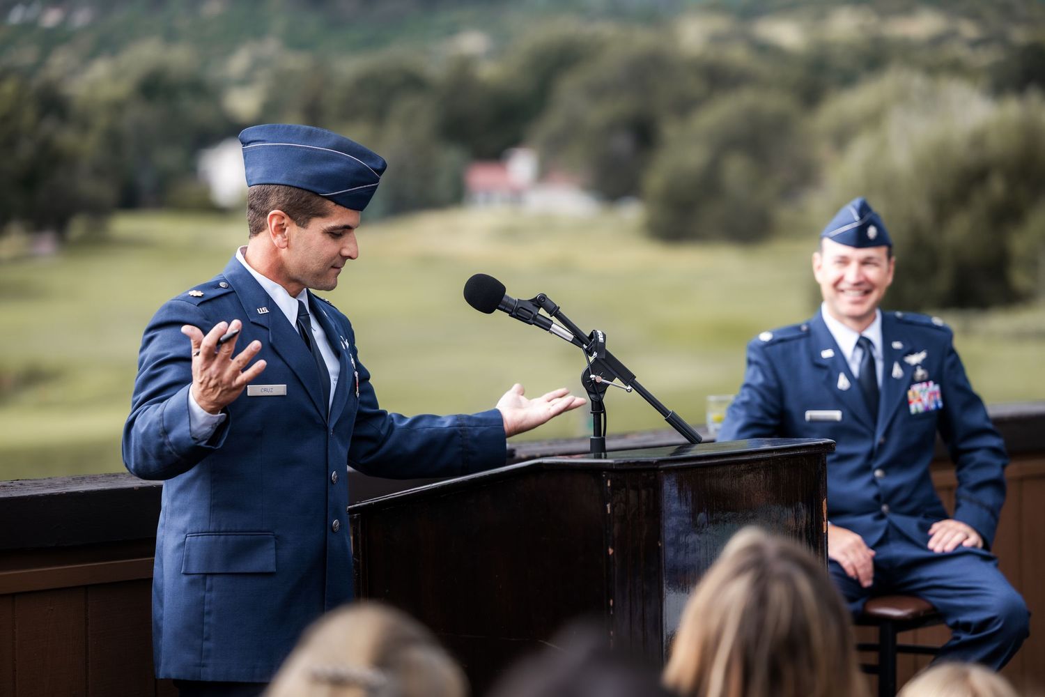 Military ceremony taking place outdoors with speakers and service members in attendance.