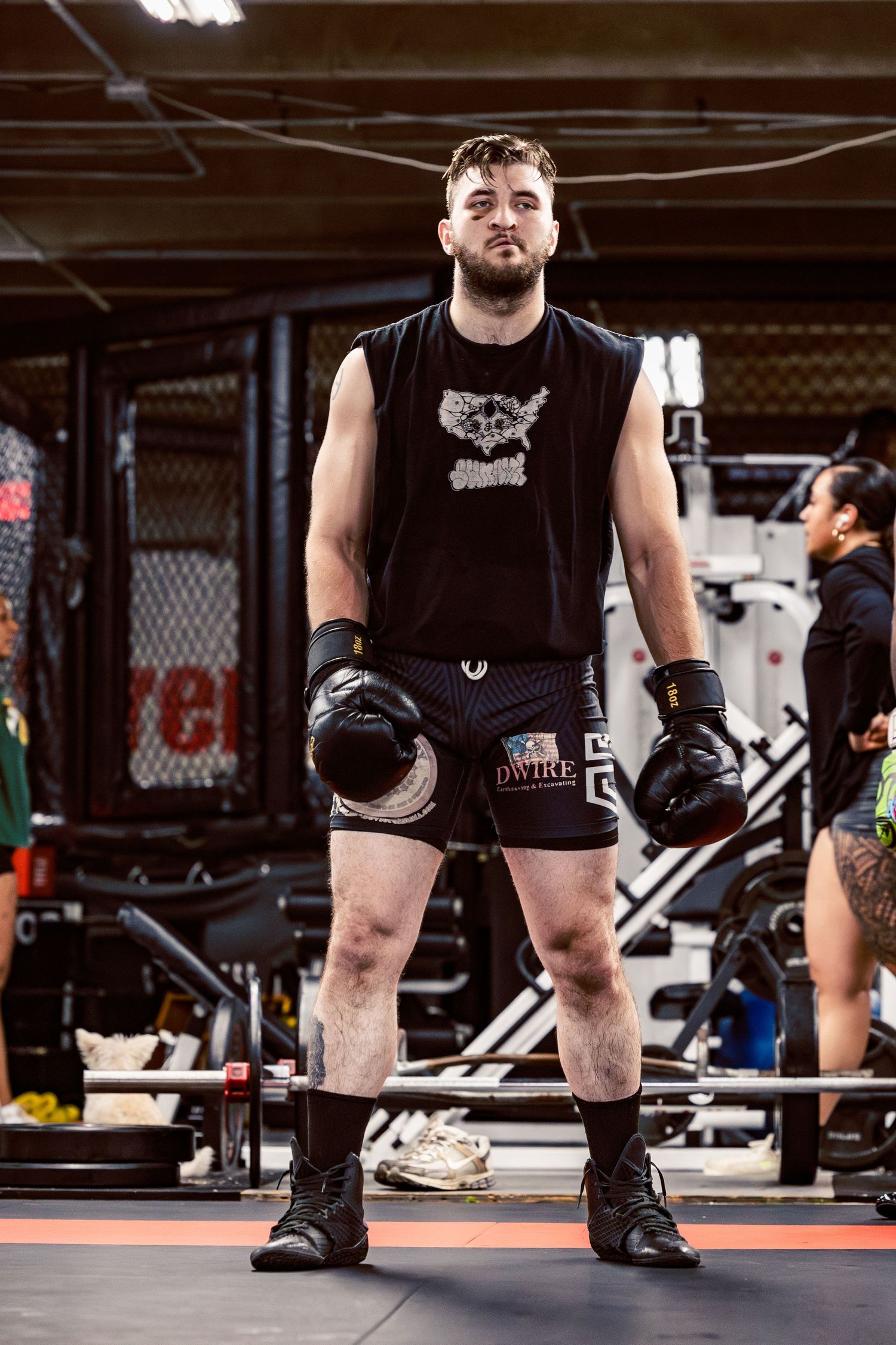 Athletes practicing weightlifting techniques in a combat sports training facility.