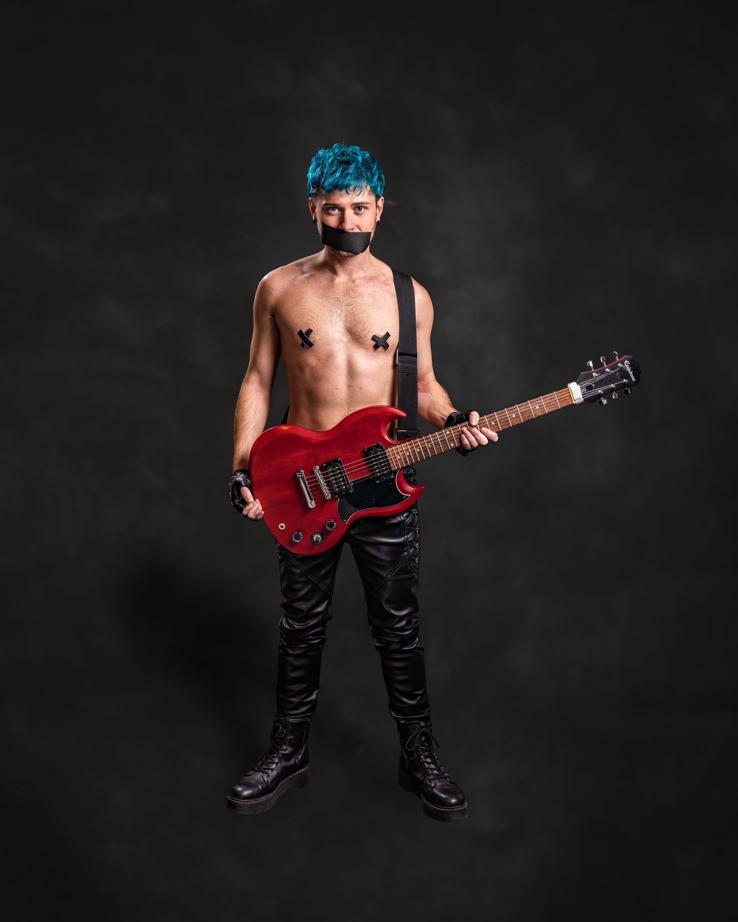 Shirtless musician with blue hair holding red electric guitar, wearing black leather pants and boots, with butterfly pasties.