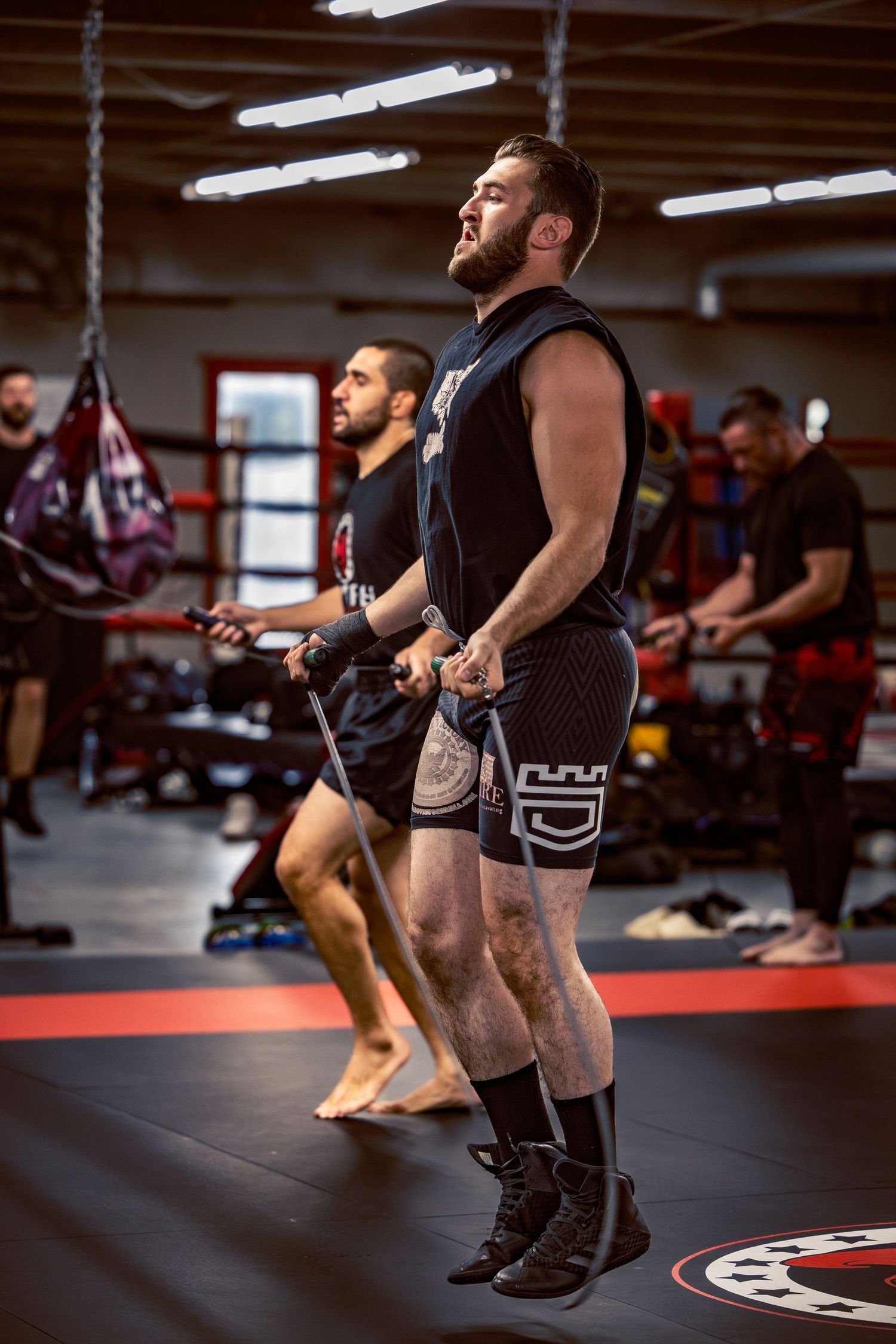 Fitness participants performing synchronized jumping exercises in a gym environment.