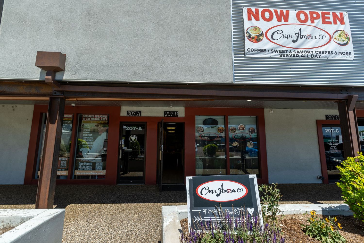 Exterior of Casa Juana Co. restaurant with Now Open sign, storefront windows, and landscaped entrance.