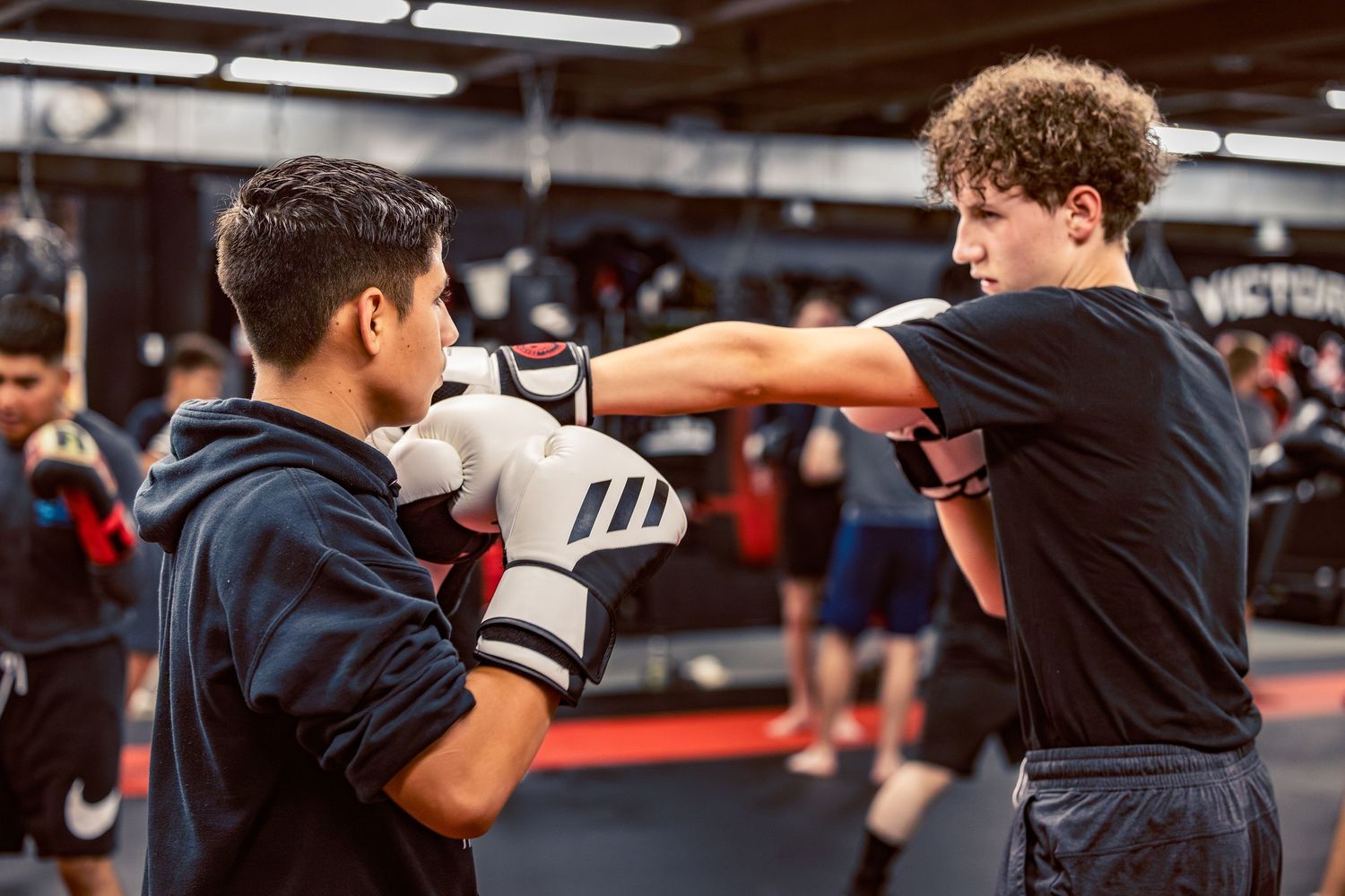 Combat sports practitioners working on defensive techniques during a group training session.