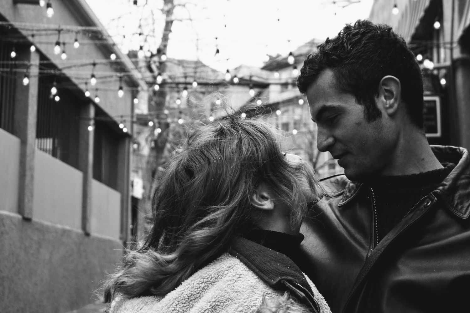 A black and white romantic moment captured between two people on a city street.