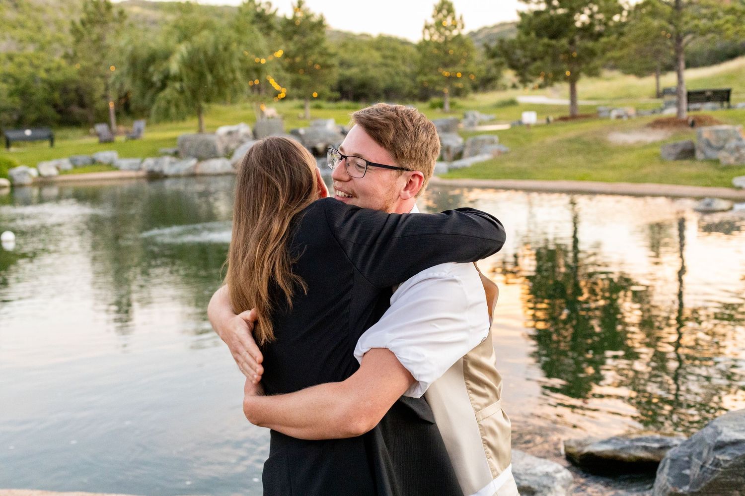 Wedding celebration by a scenic lakeside with mountains in the background.