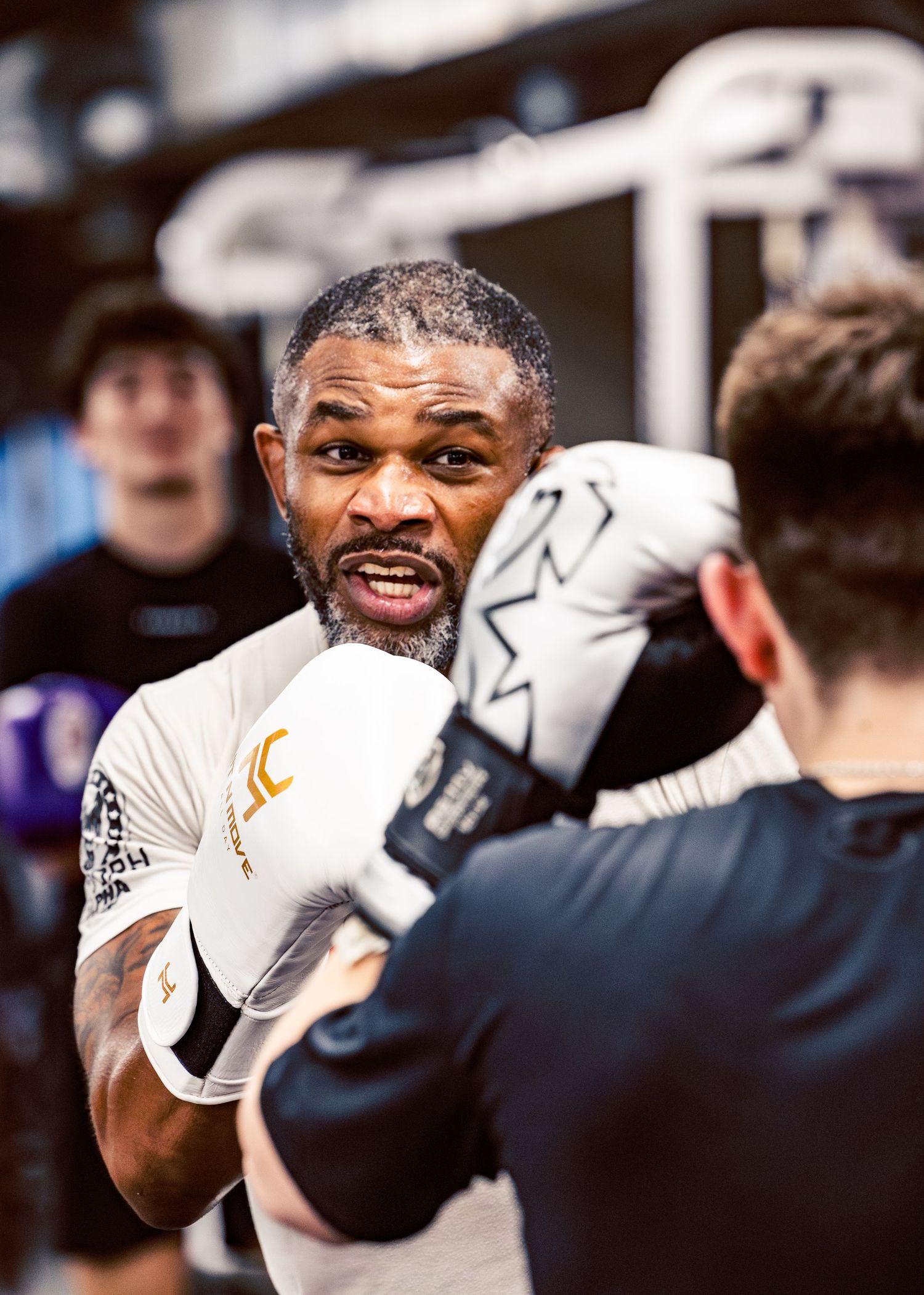 Boxers sparring in a professional training gym with white gloves.