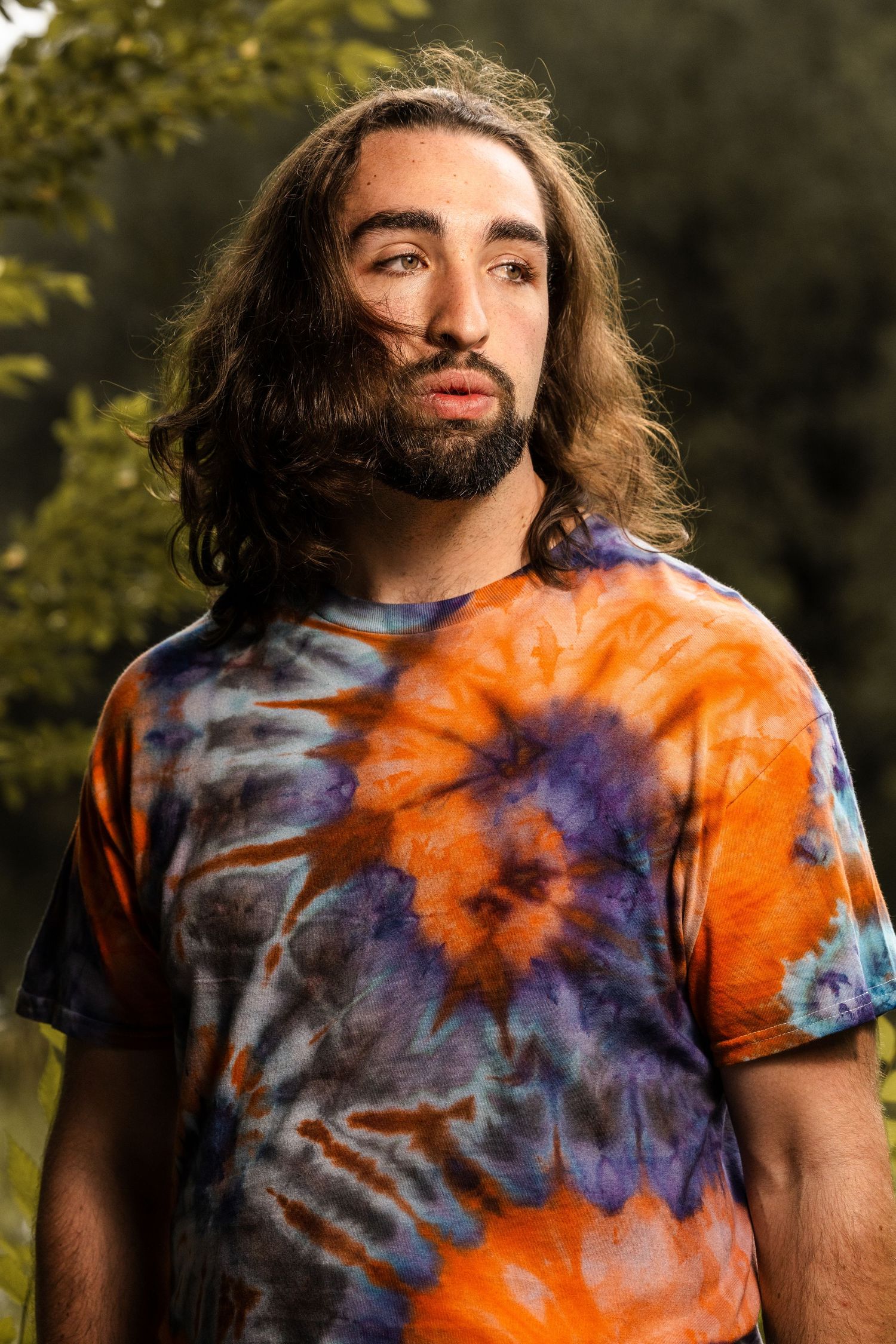 Outdoor portrait with natural lighting highlighting a colorful tie-dye t-shirt design.