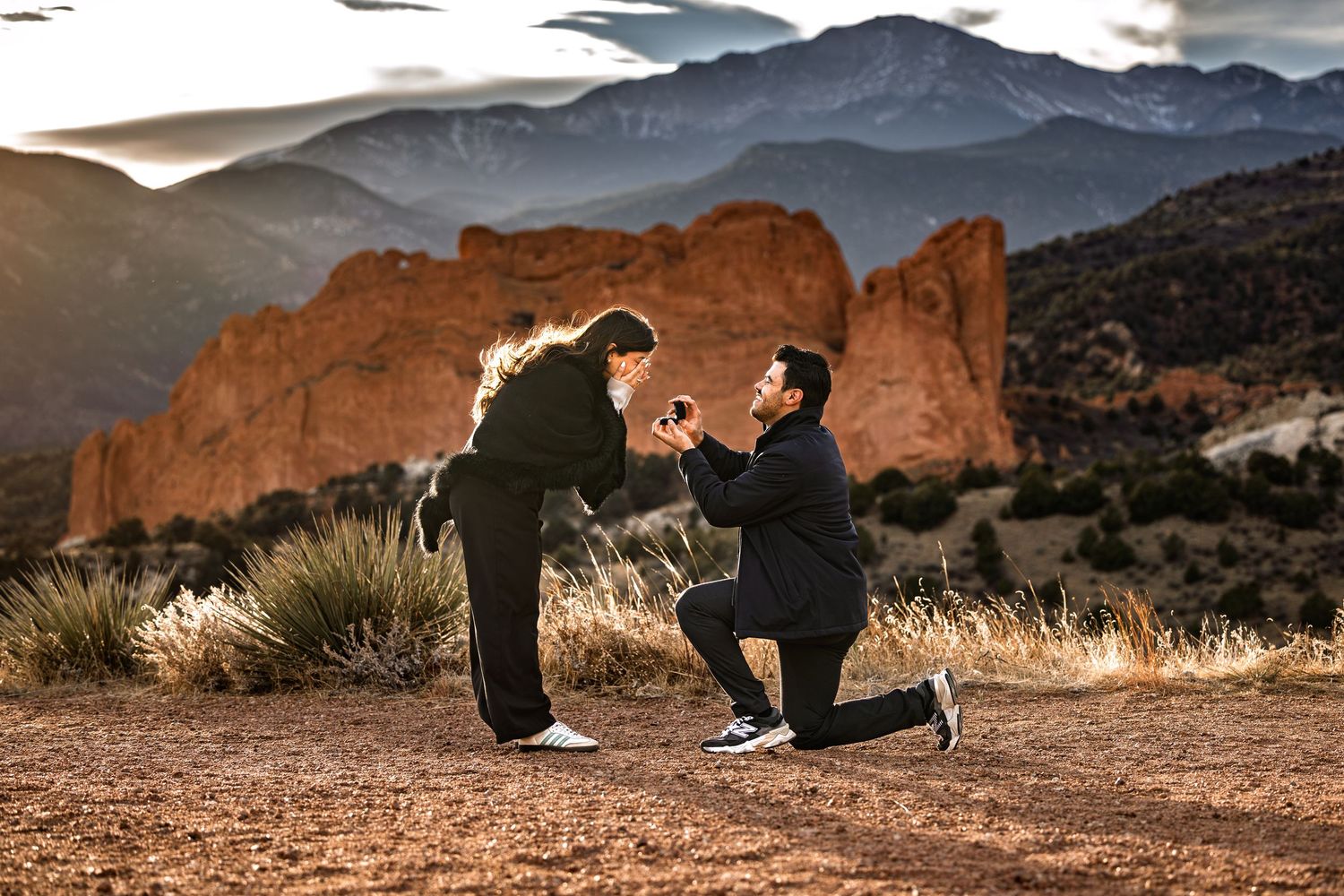 A proposal silhouette at sunset in Garden of the Gods park with red rock formations and mountains in the background.