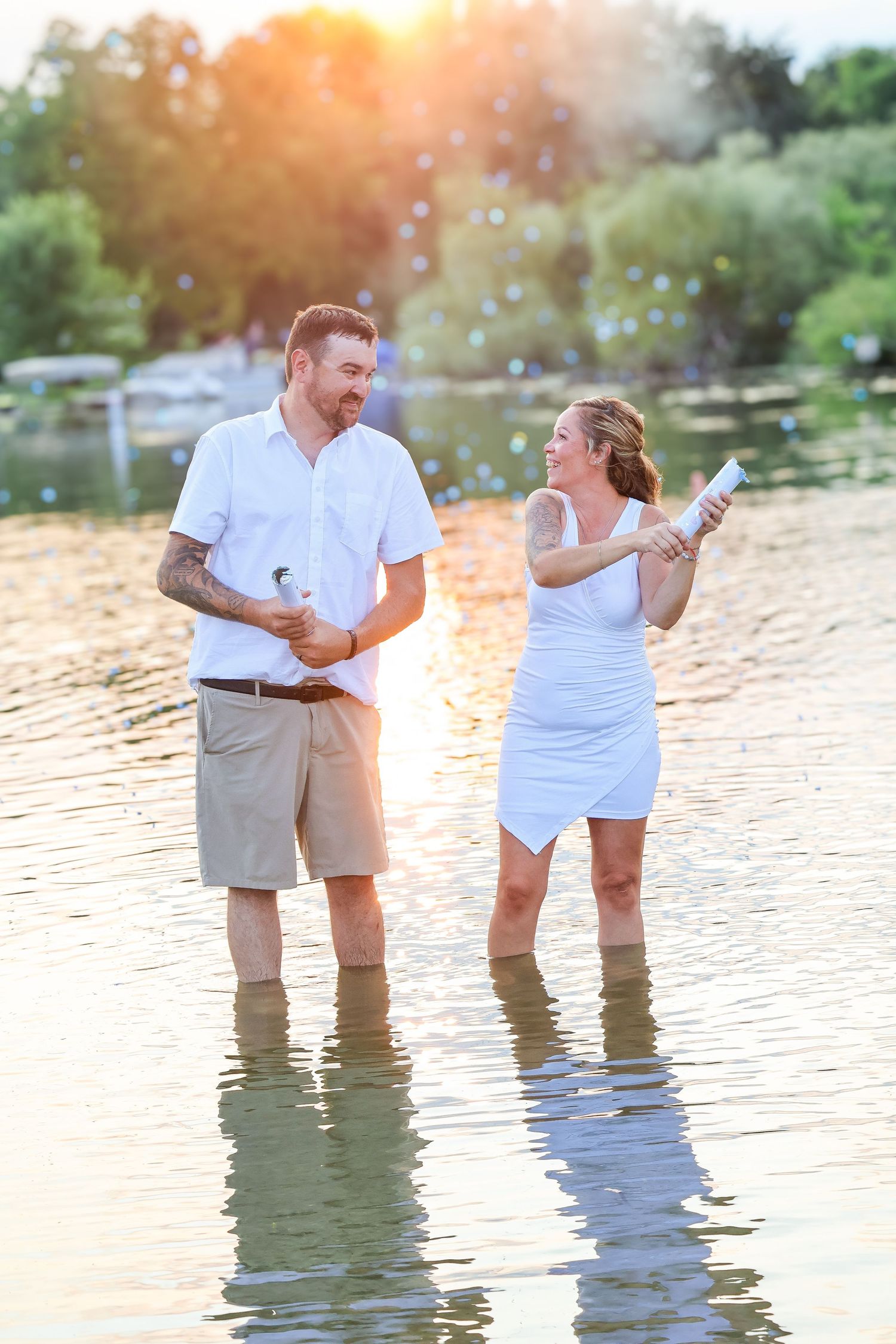 Couple standing in lake at sunset with bubbles around them.