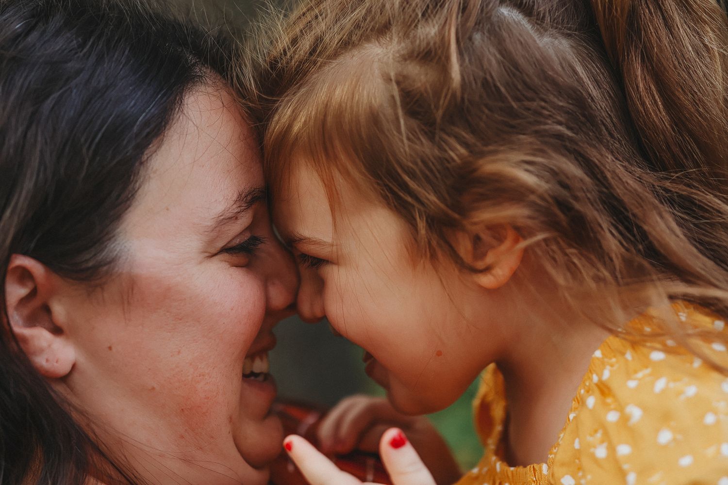 Loving mother and daughter smiling and touching foreheads in a tender close-up moment.