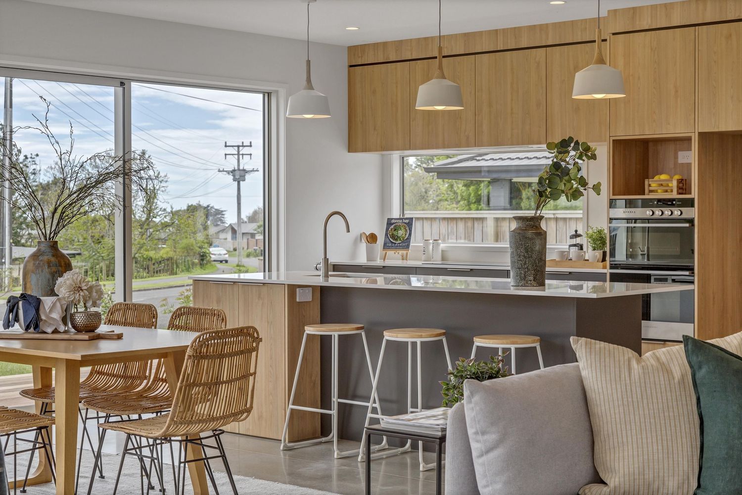 Modern open concept living space with wood paneled walls, pendant lights, and large windows overlooking outdoor scenery.