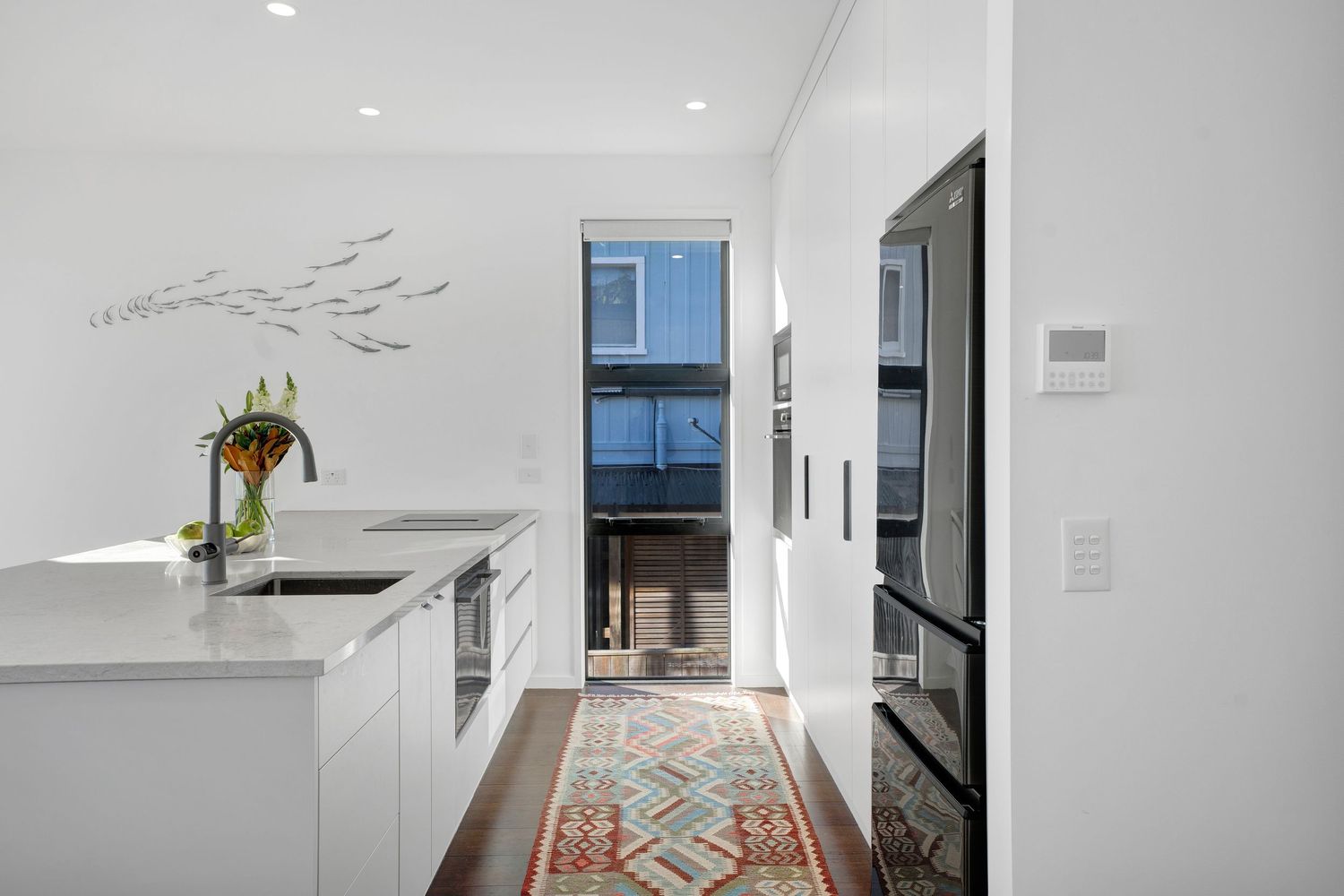 A bright modern interior space with white walls and minimalist decor features a sleek pendant light fixture.