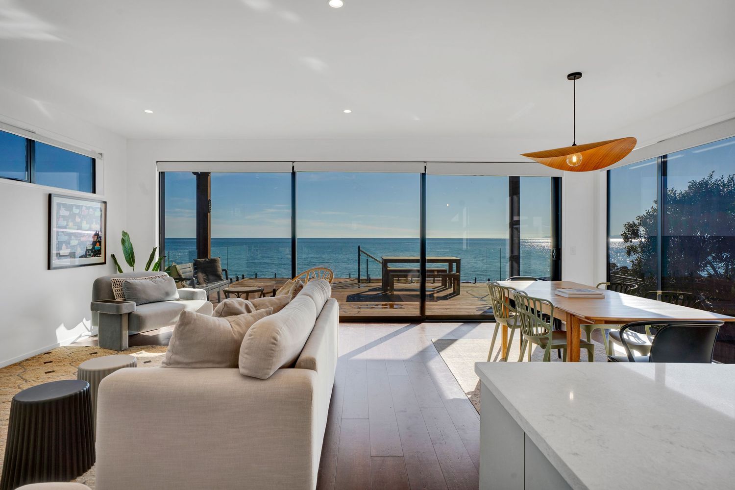 Modern lounge area with coastal views through expansive windows and minimal white interior design elements.