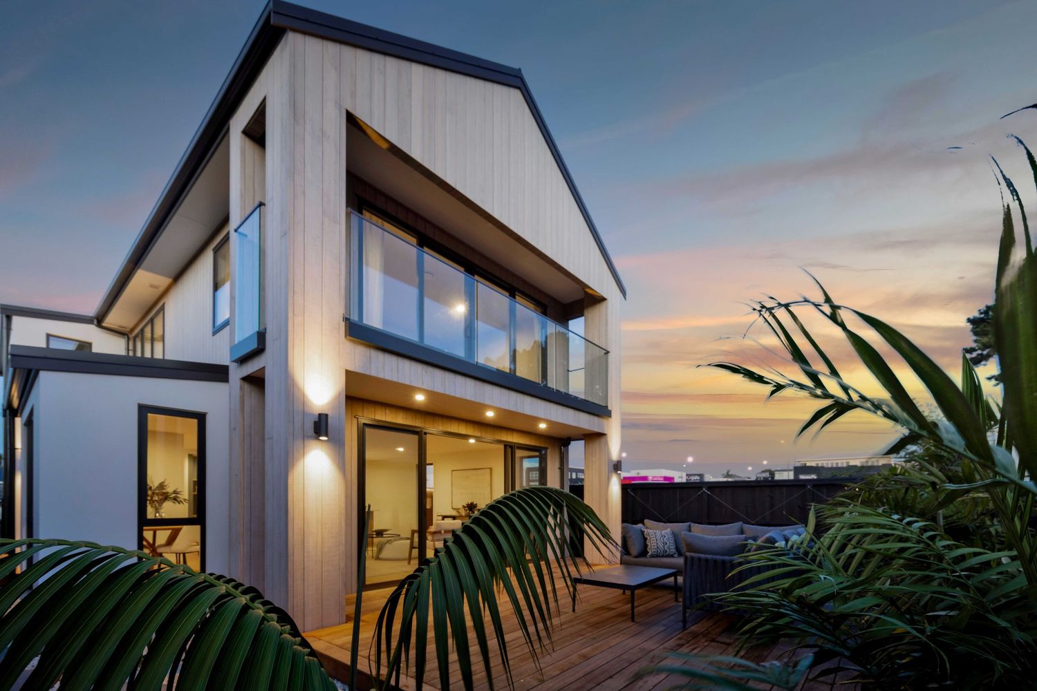 Striking modern home exterior with angular roof design lit up at dusk.