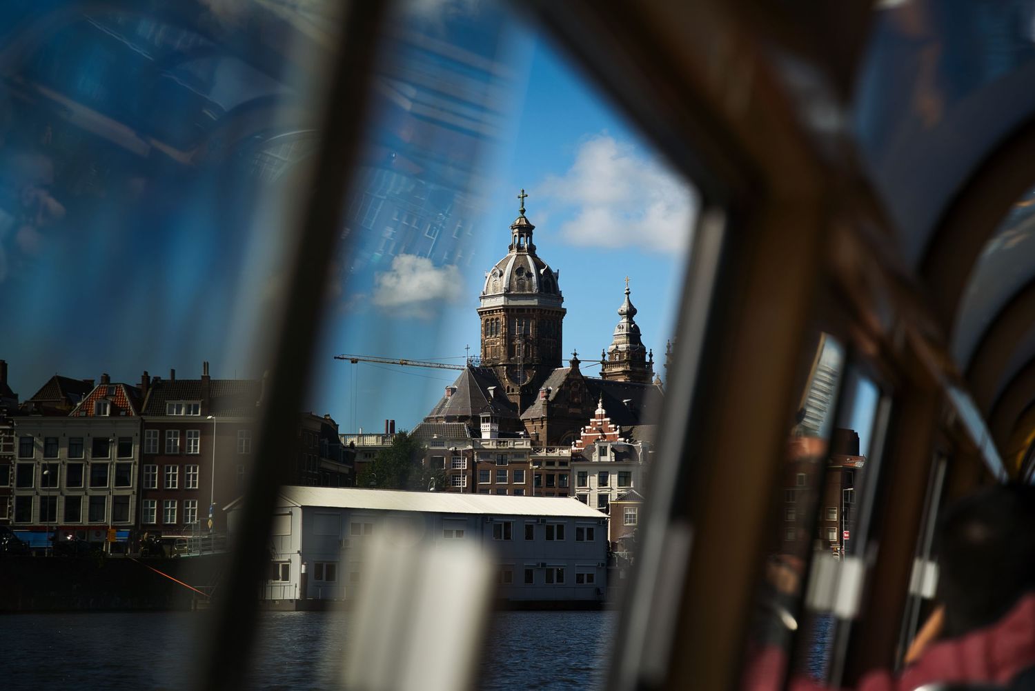 View of an Amsterdam church dome and historic canal buildings reflected in a window