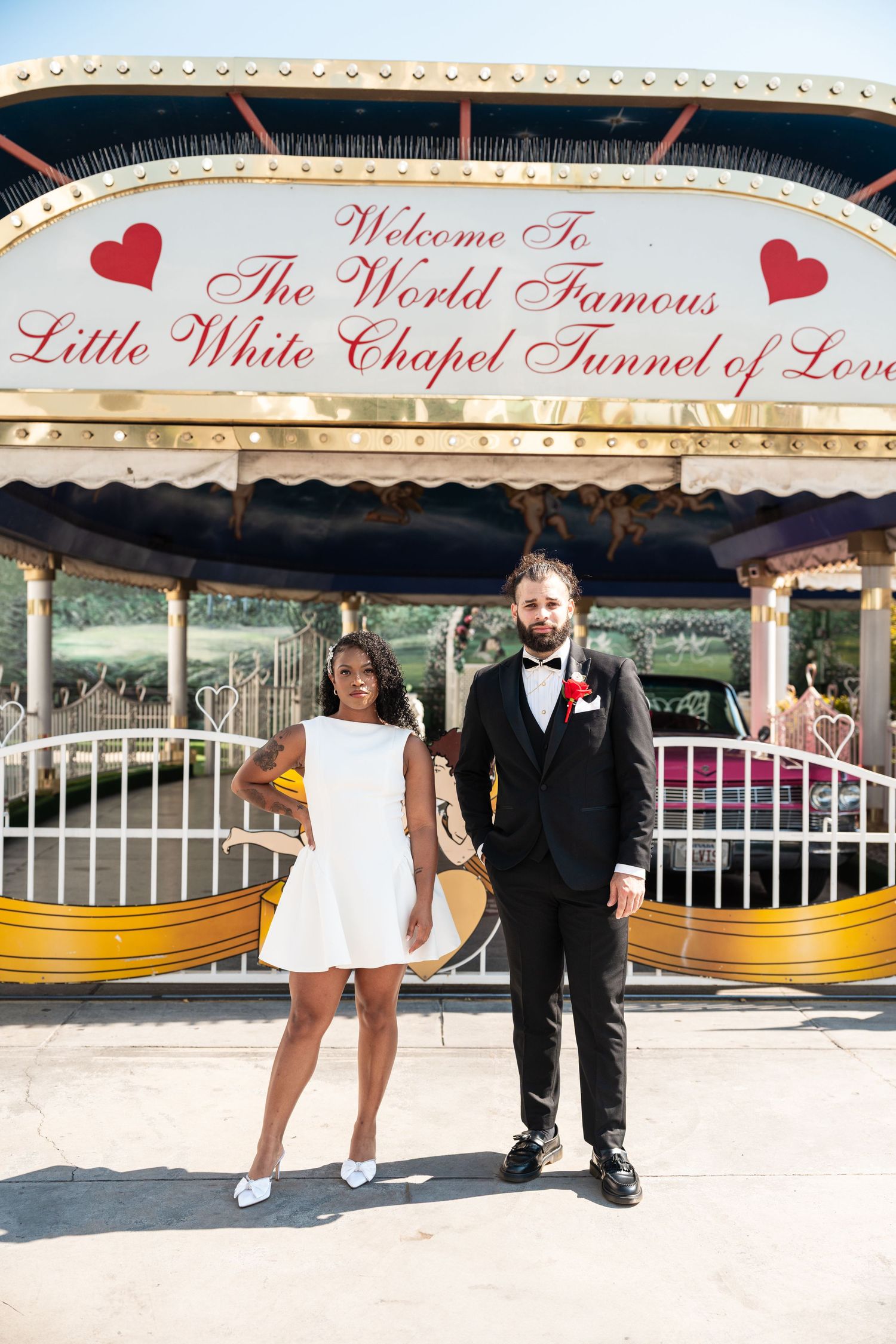 A couple poses under the World Famous Little White Chapel Tunnel of Love sign.