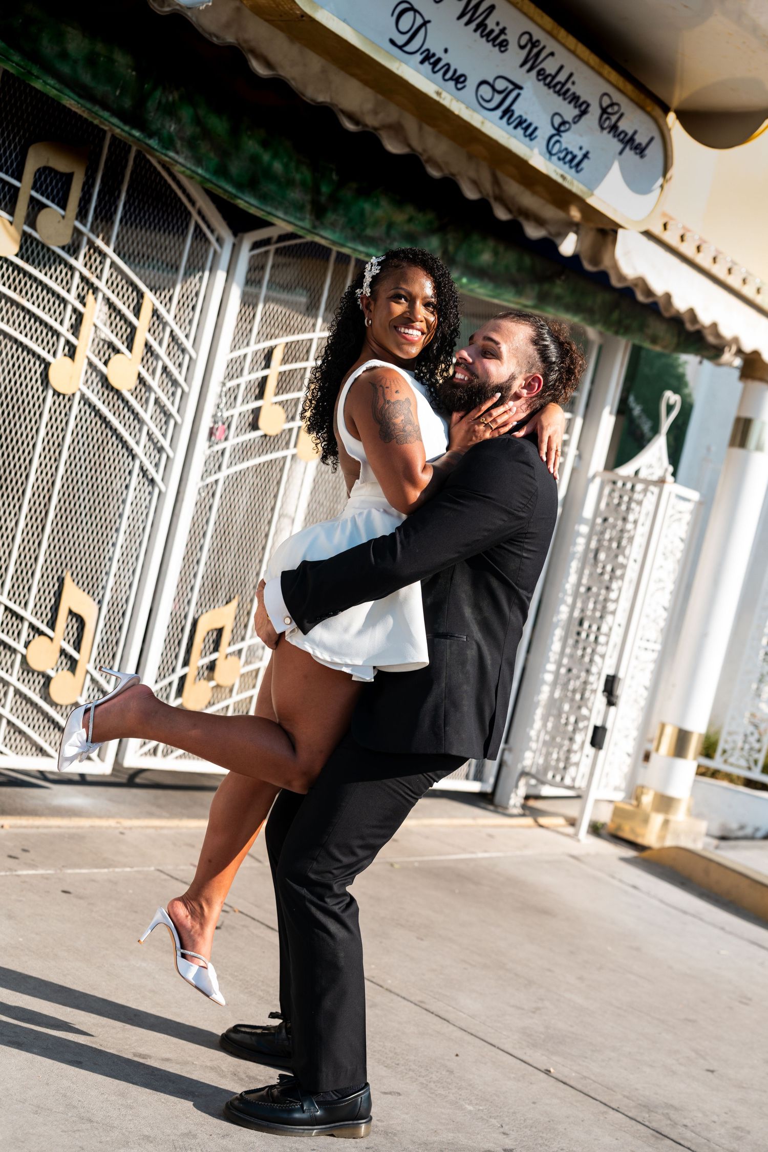 A playful wedding couple embrace outside the Little White Chapel.