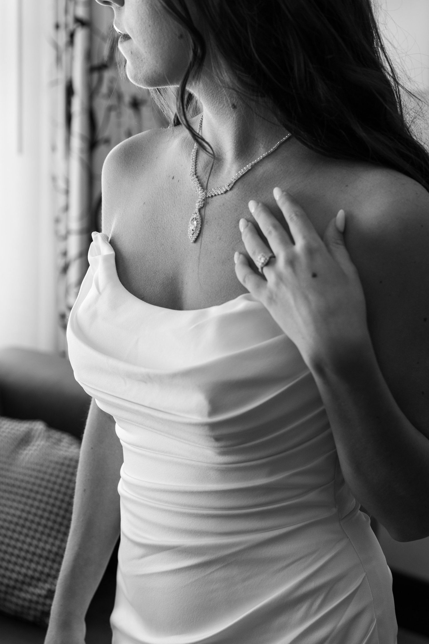 Black and white portrait of delicate jewelry details and white clothing.