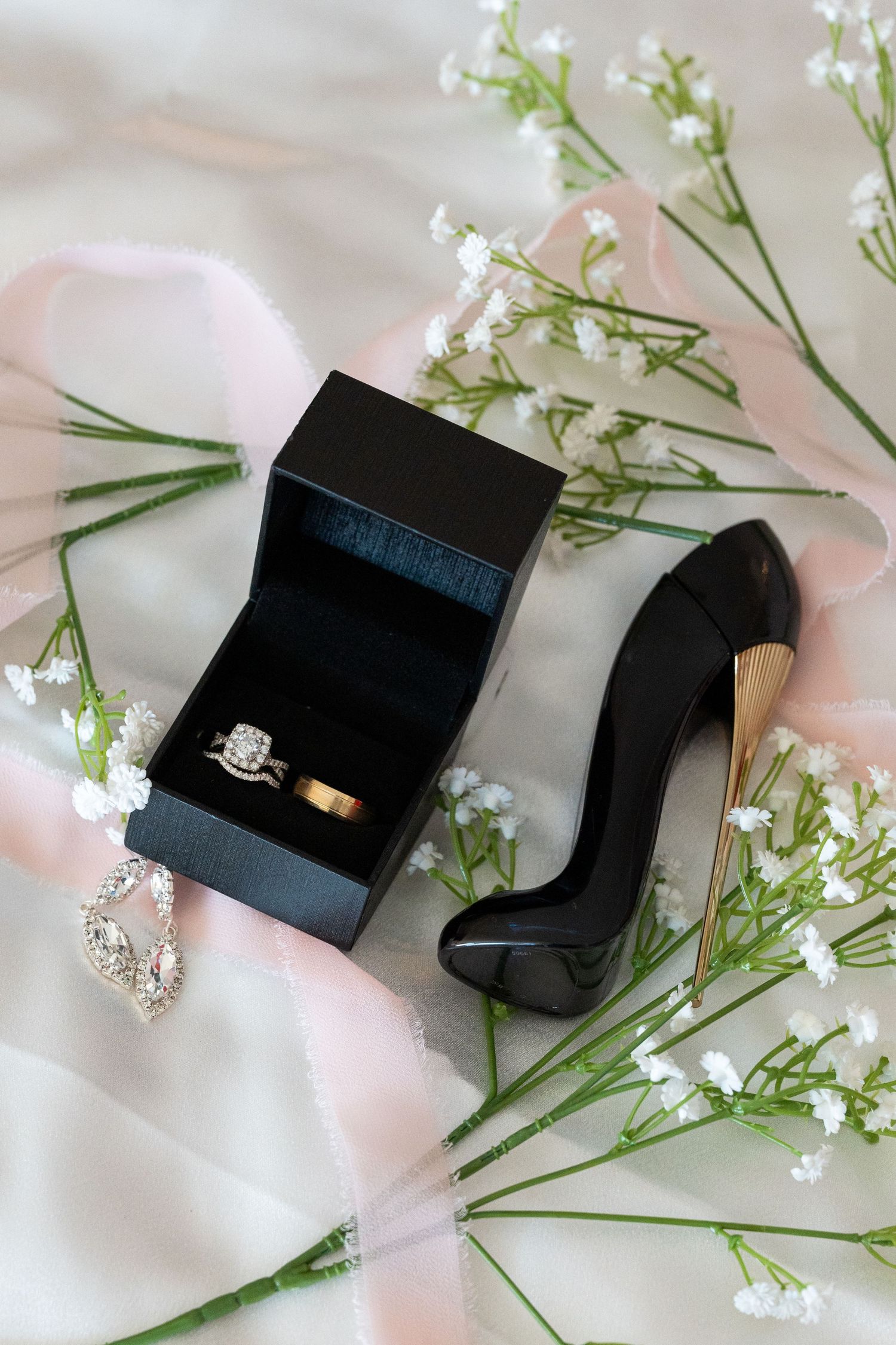 Black ring box with rings displayed among delicate white baby's breath flowers.