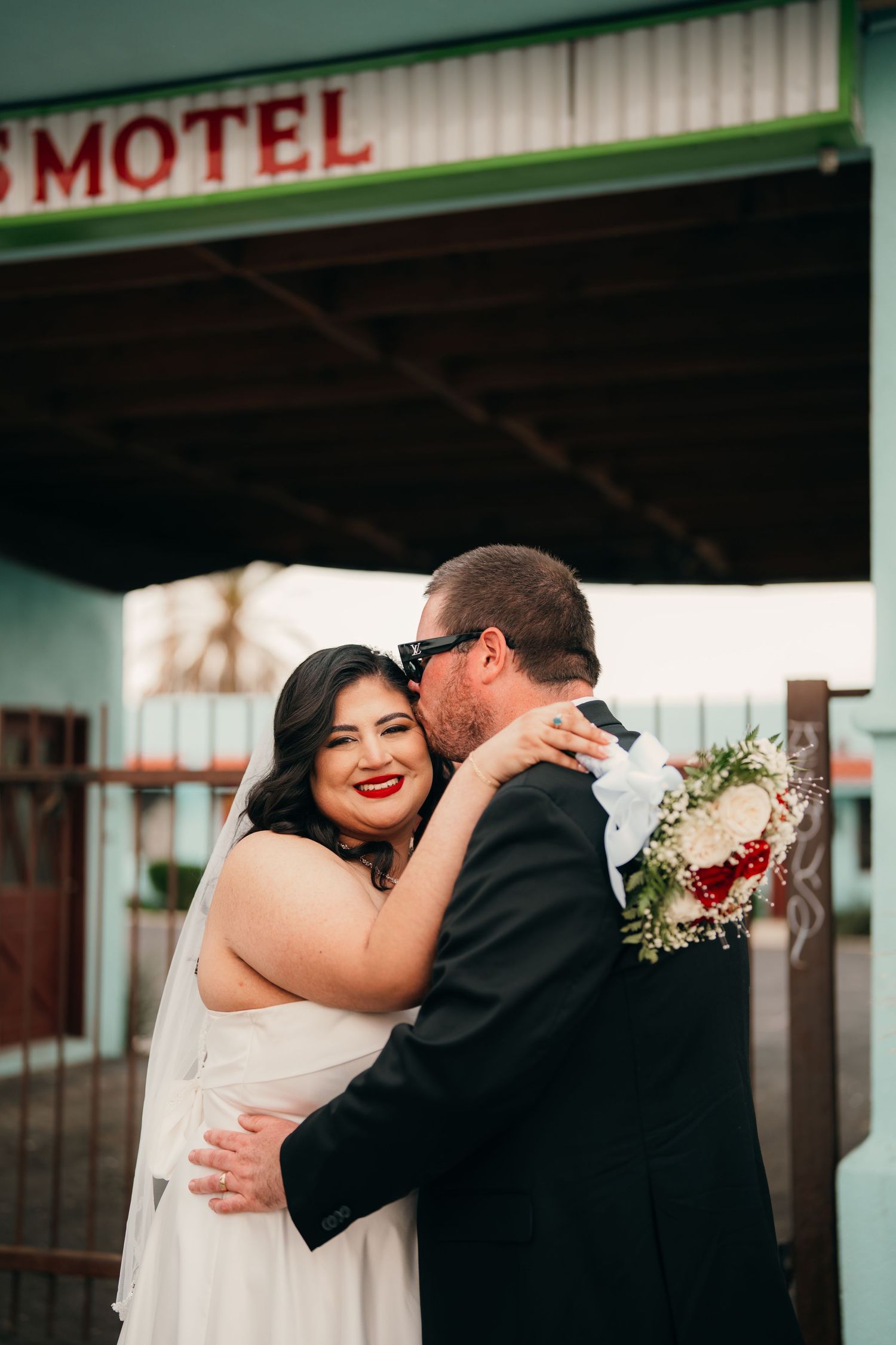 A wedding couple embraces in front of a retro motel sign during their photoshoot.