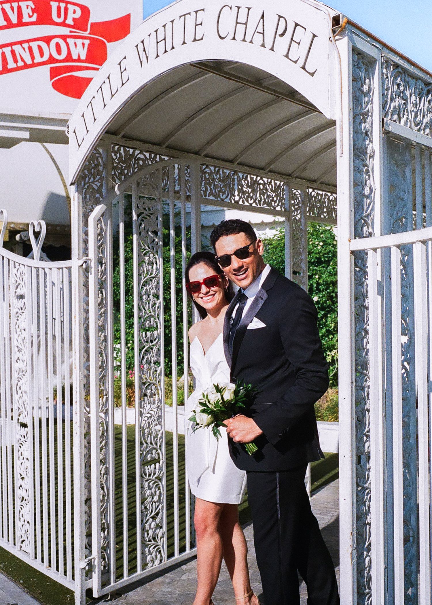 A couple poses under the iconic Little White Chapel entrance arch in Las Vegas.