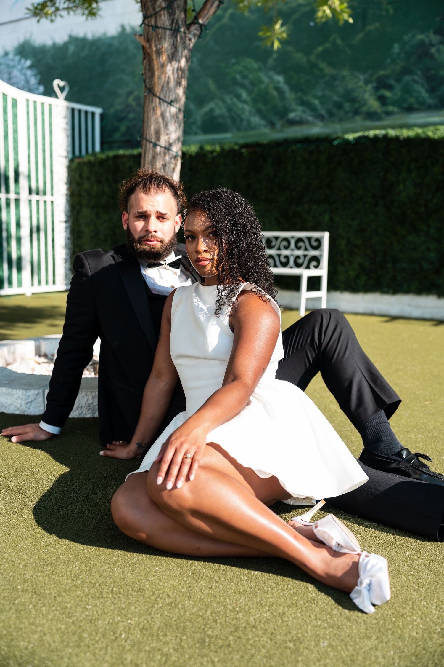 A newlywed couple relaxes on artificial turf during their outdoor wedding photo session.