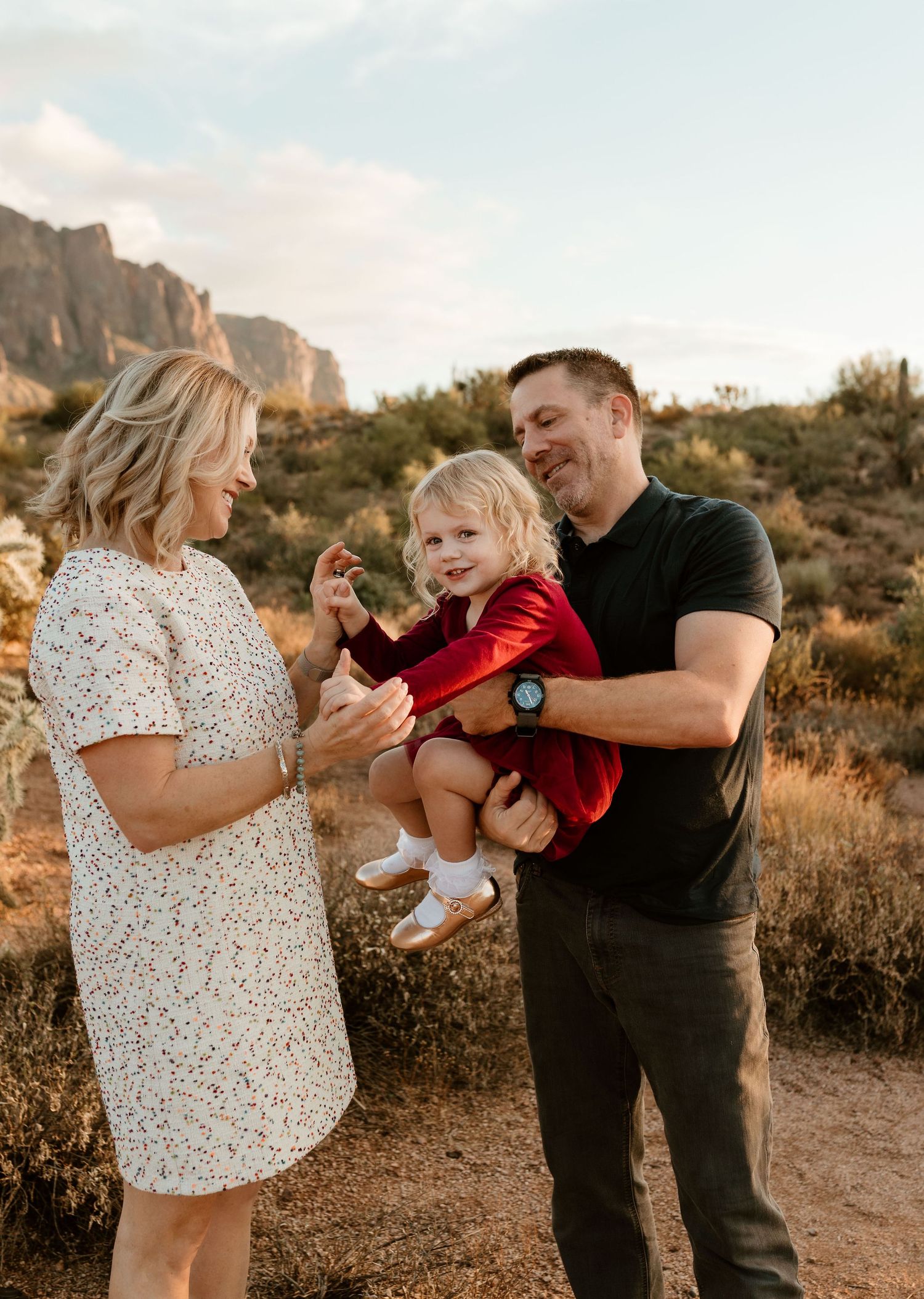 Family sharing playful moments together in desert landscape during golden hour.
