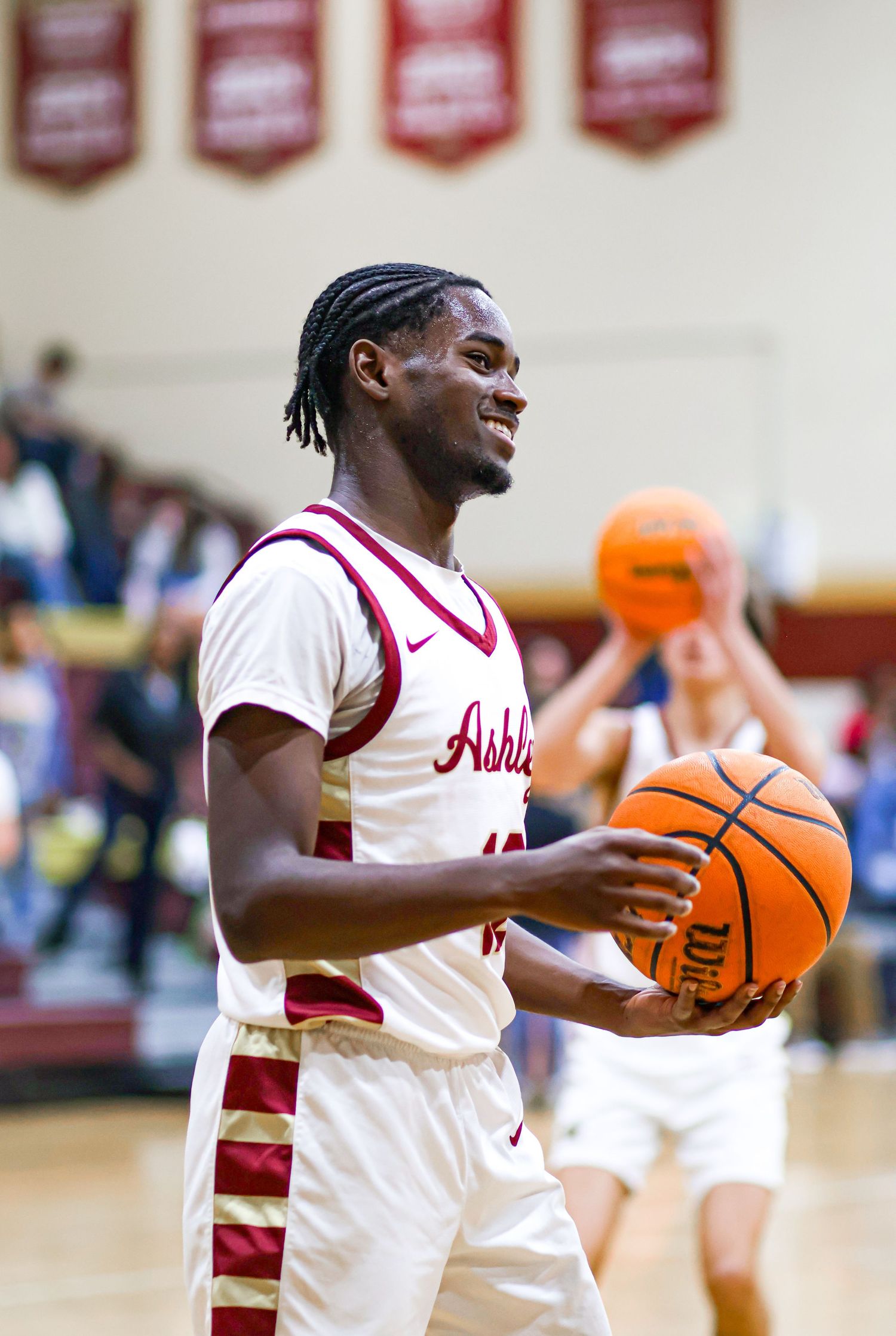 Basketball player in white uniform dribbles an orange ball during a game.
