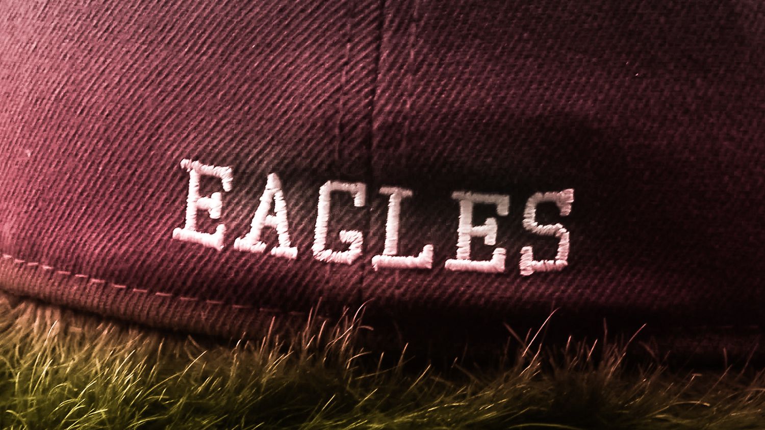 A close-up view of a maroon baseball cap with 'EAGLES' text embroidered on it.