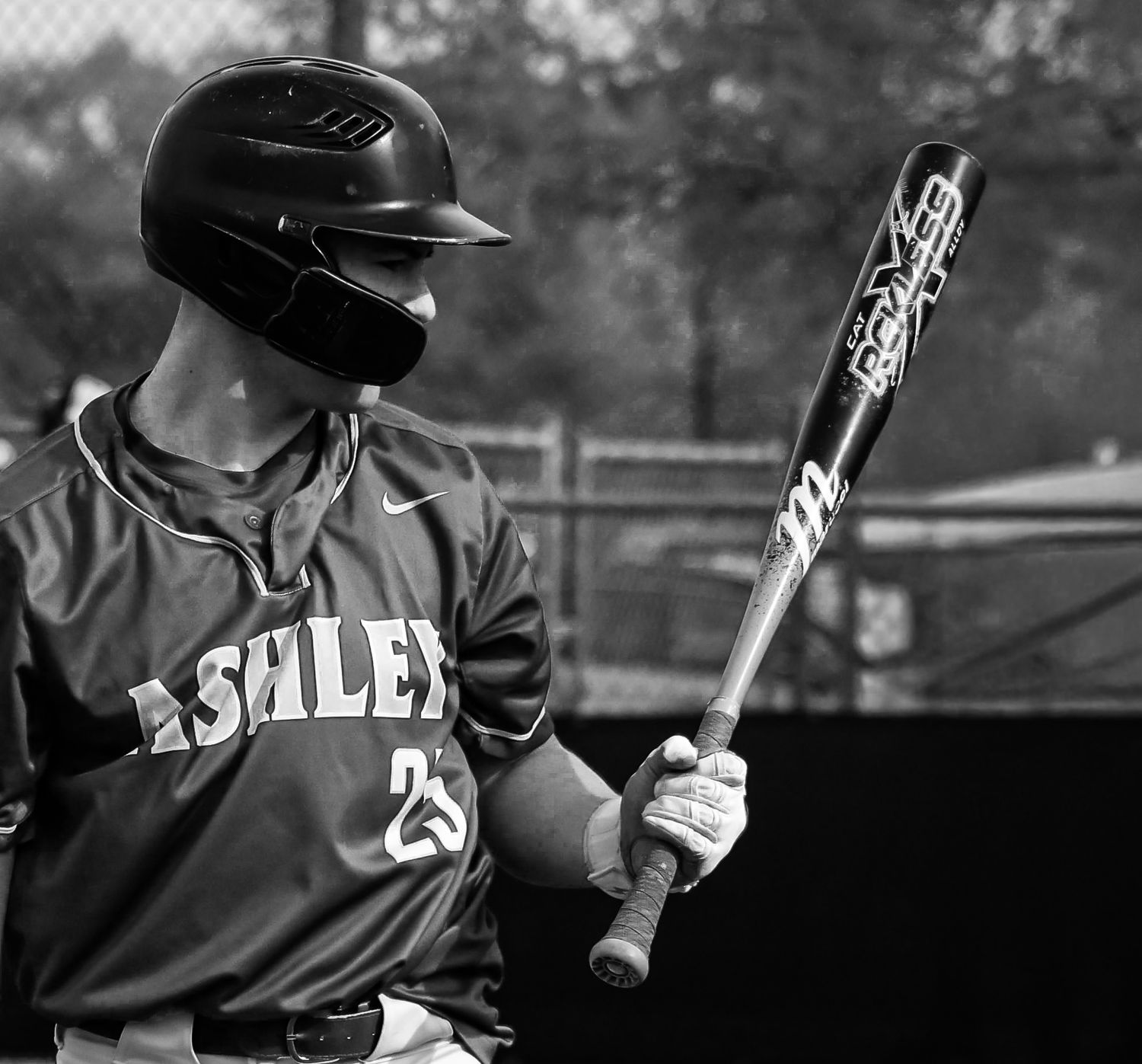 A baseball player in a dark uniform holds a bat at the plate during a game.