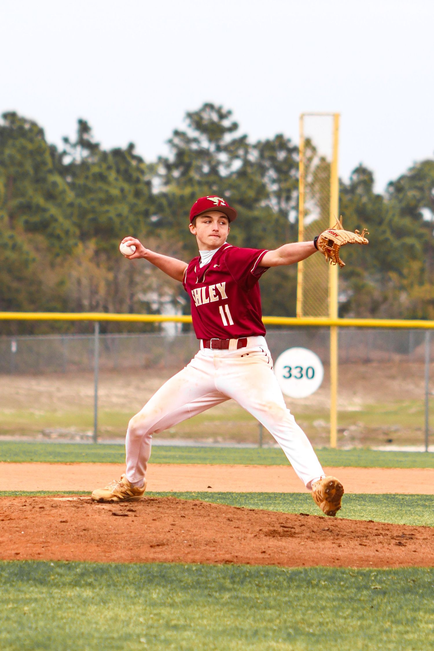 Baseball pitcher in red uniform demonstrates follow-through motion sequence during game on dirt mound.