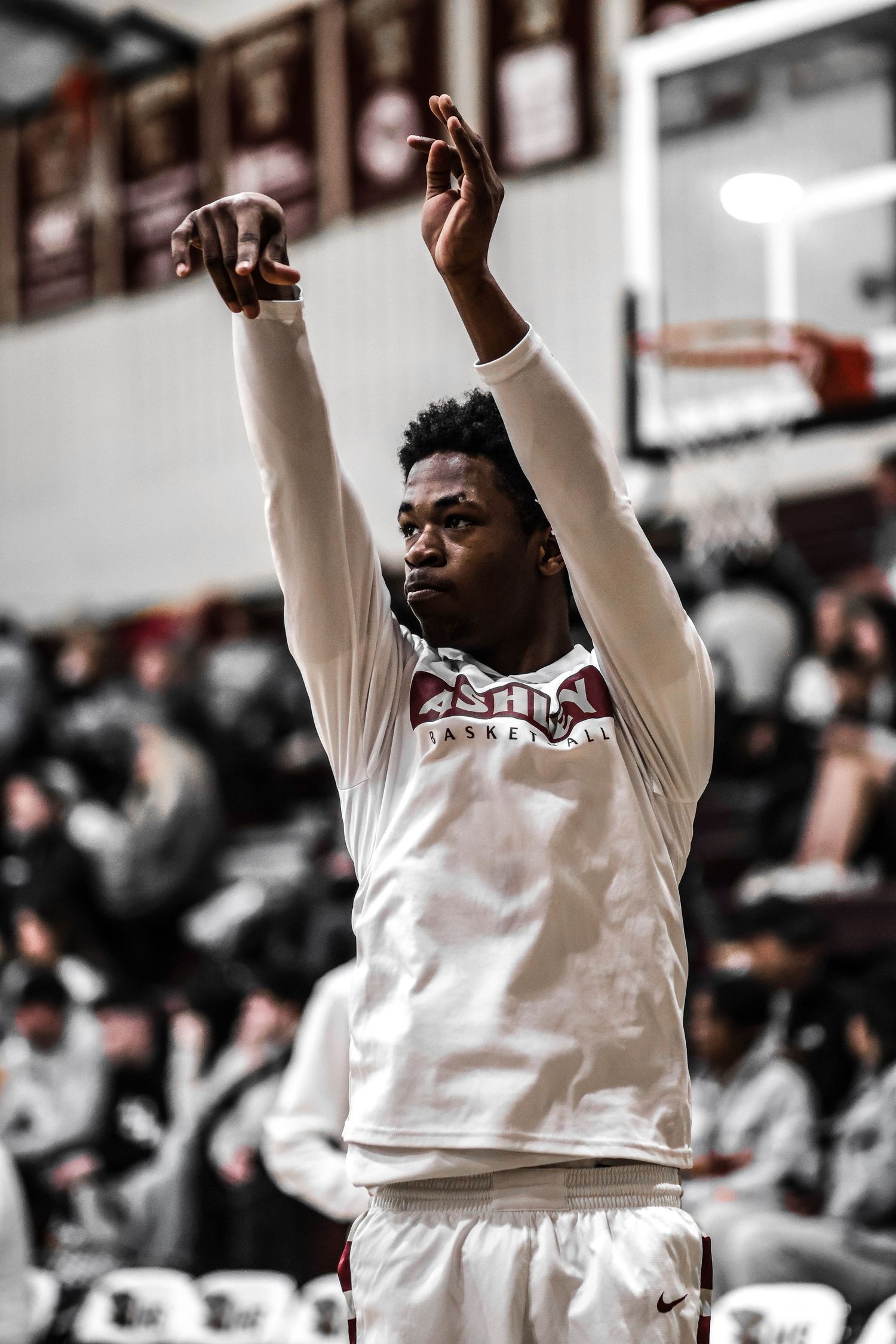 Basketball player in white jersey celebrates with arms raised during game.