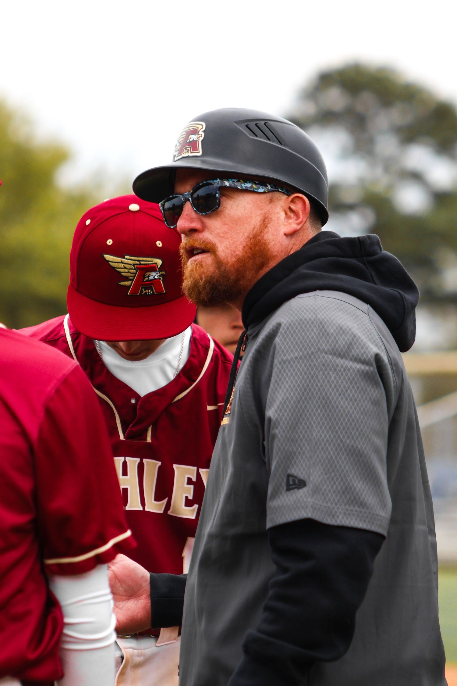 Baseball coaches in red uniforms and black jackets have an intense discussion during a game.
