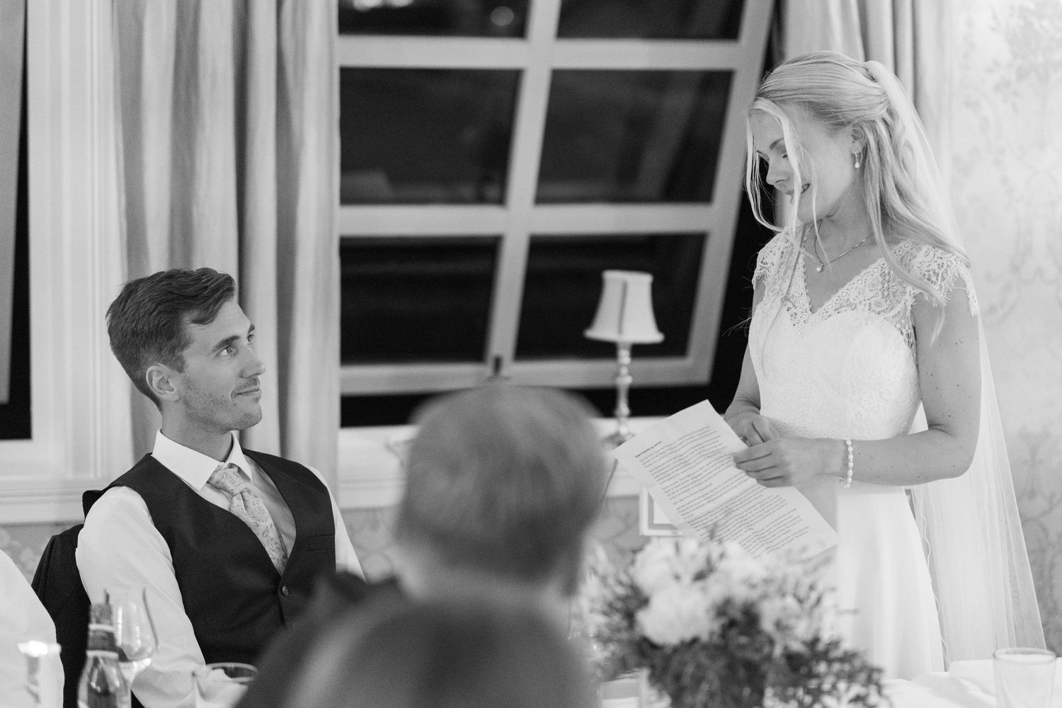 Black and white photo of bride giving a heartfelt speech at wedding reception dinner.