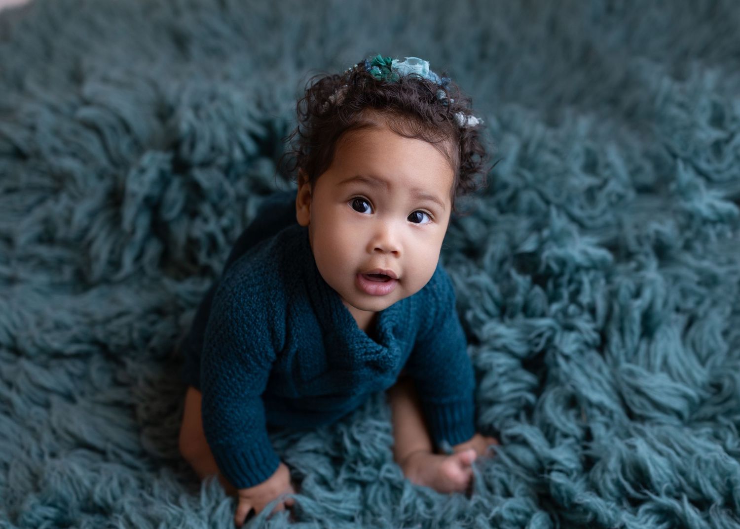 Baby portrait session on textured teal blanket showing developmental milestones.