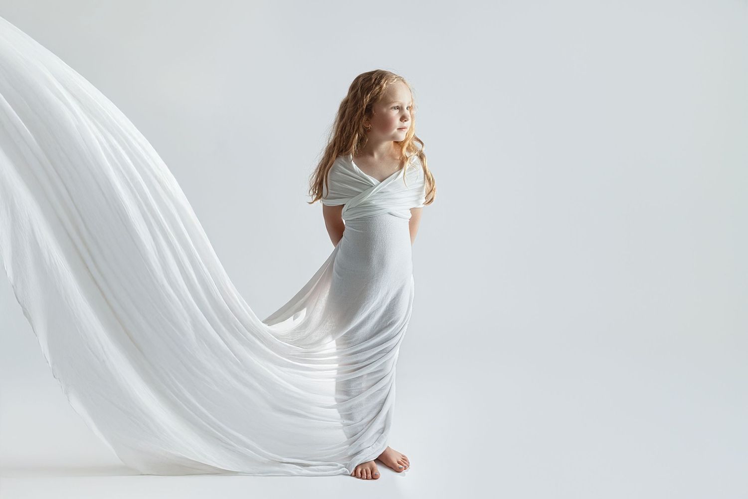 Flowing white fabric creates dramatic movement in studio photoshoot.