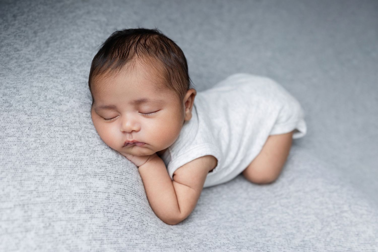 A sleeping baby lies peacefully in a series of connected black and white photographs showing different angles.